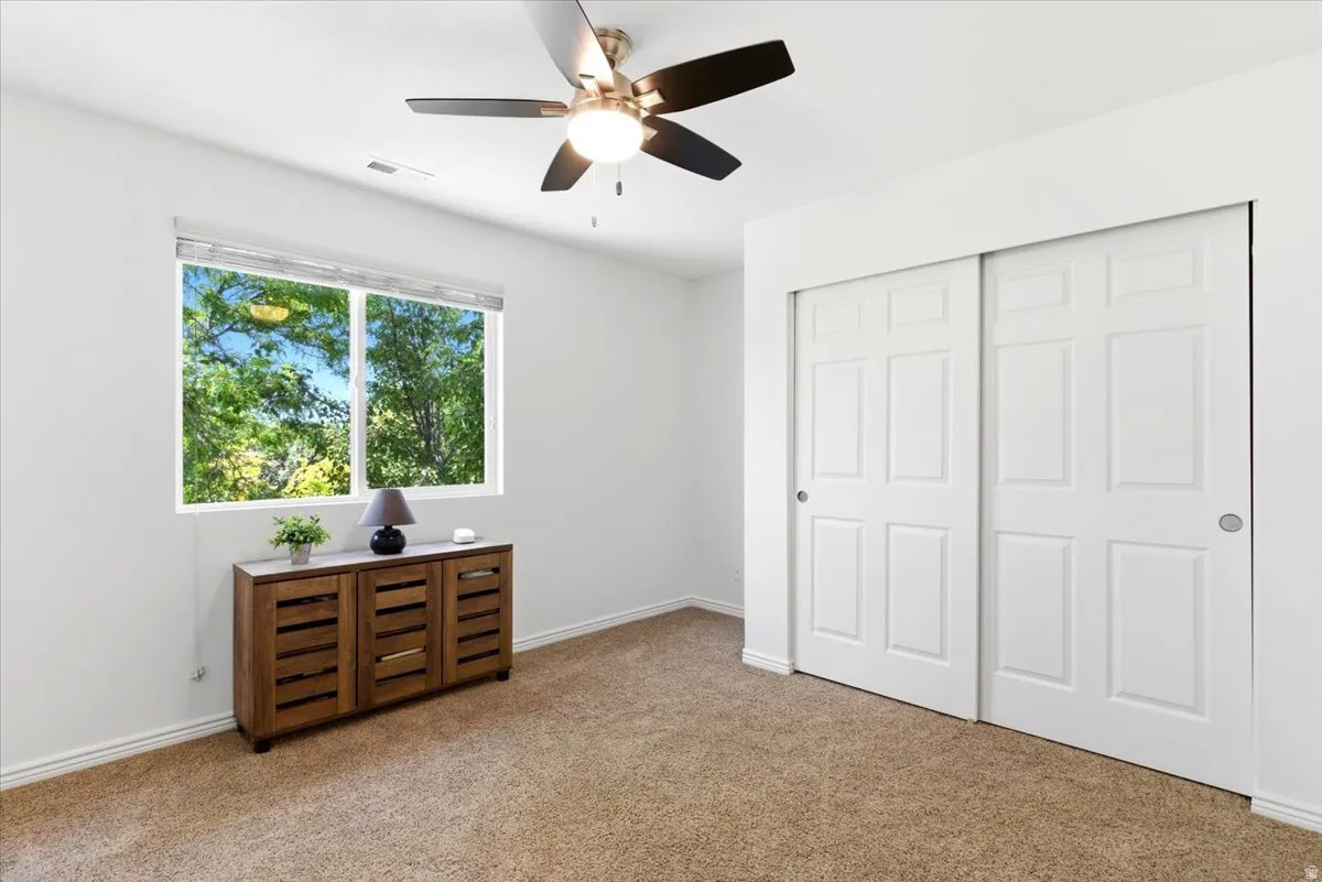 Double-pane window featuring natural light, wall-to-wall carpeting, and a ceiling fan with integrated lighting