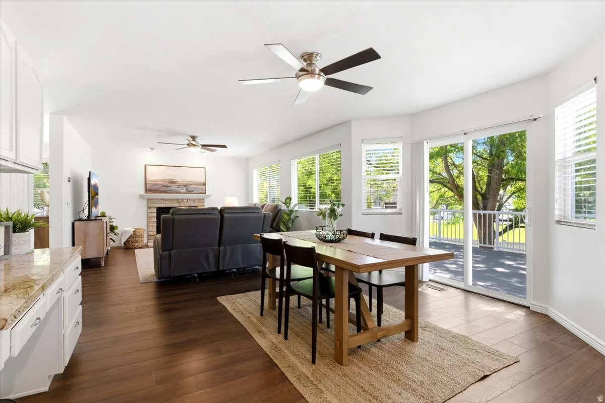 Open-concept interior featuring wood-finish flooring, white walls, and multiple ceiling fans