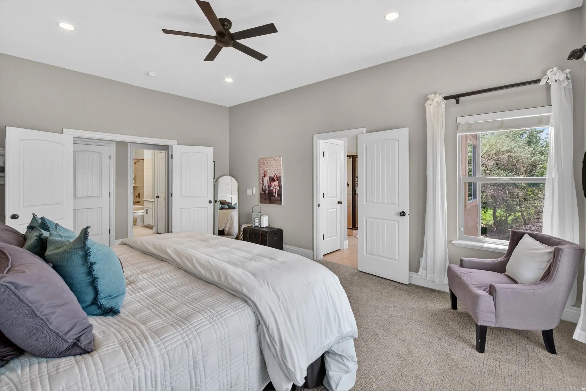 Carpeted bedroom featuring a large window, recessed lighting, and a ceiling fan