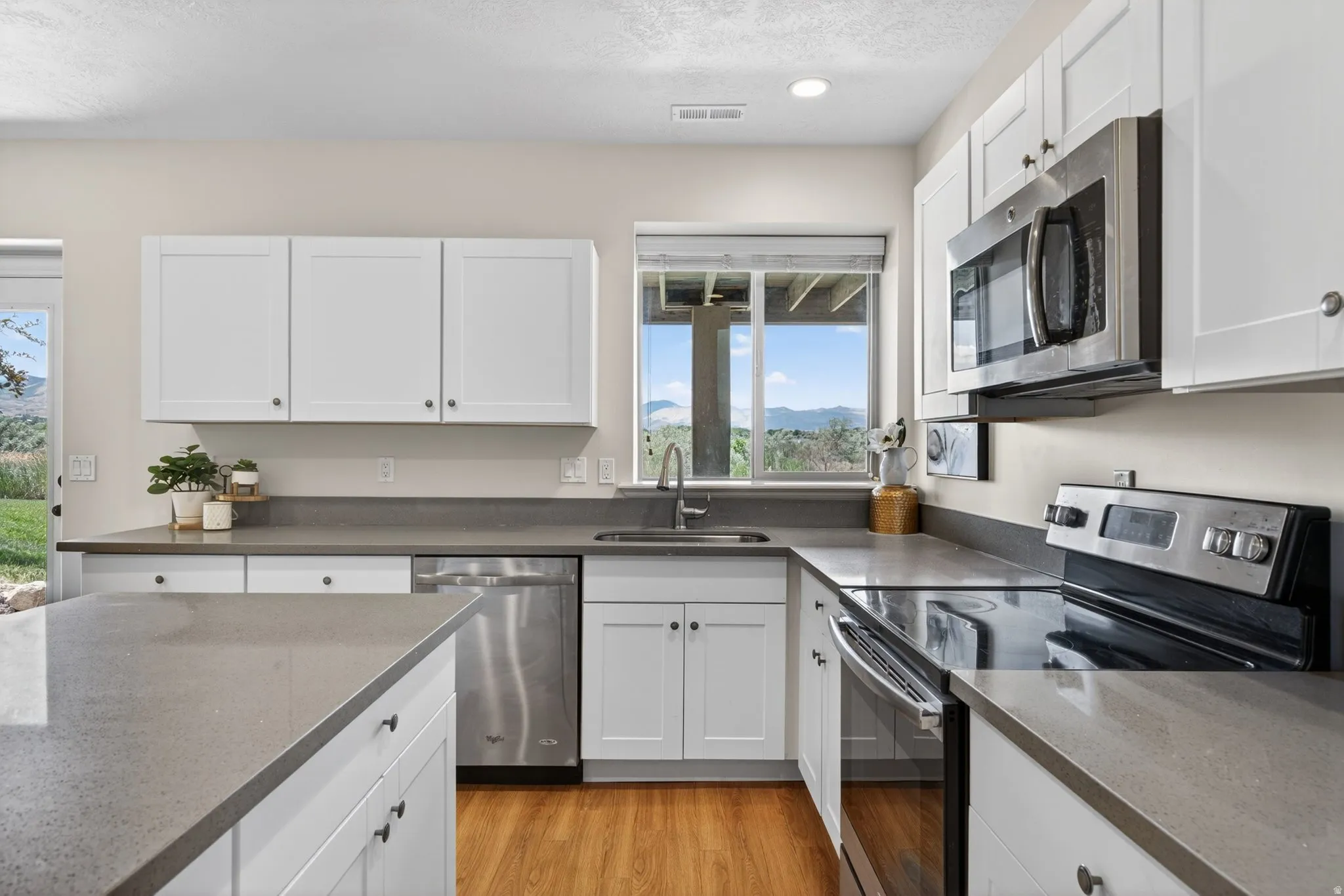 Modern kitchen featuring white shaker cabinetry and a built-in oven with a glass cooktop
