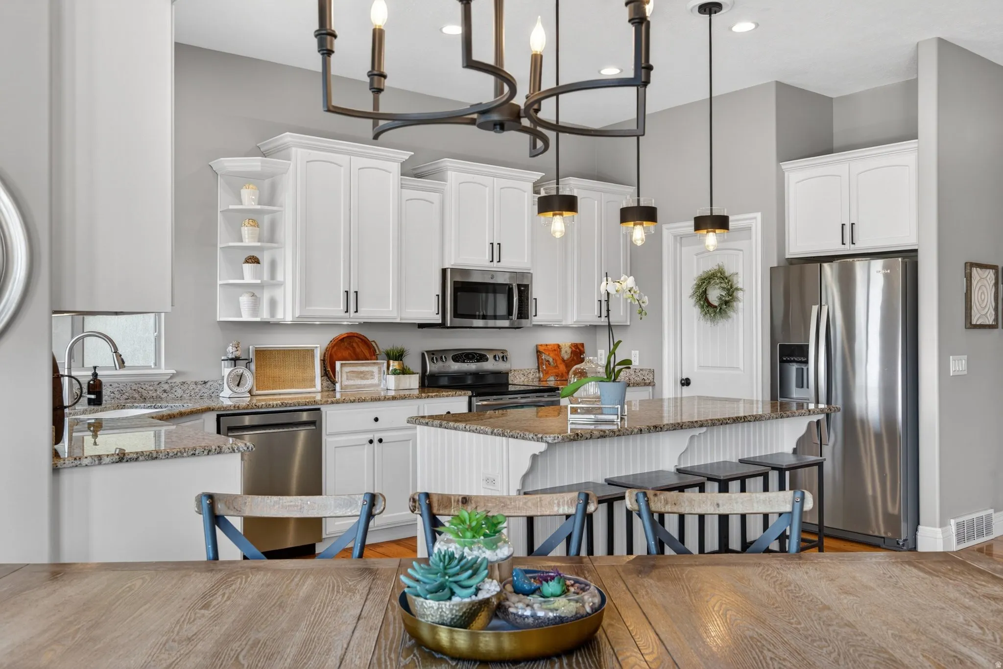 Kitchen featuring white cabinetry, stainless steel appliances, speckled stone countertops, a central island with bar seating, and recessed lighting