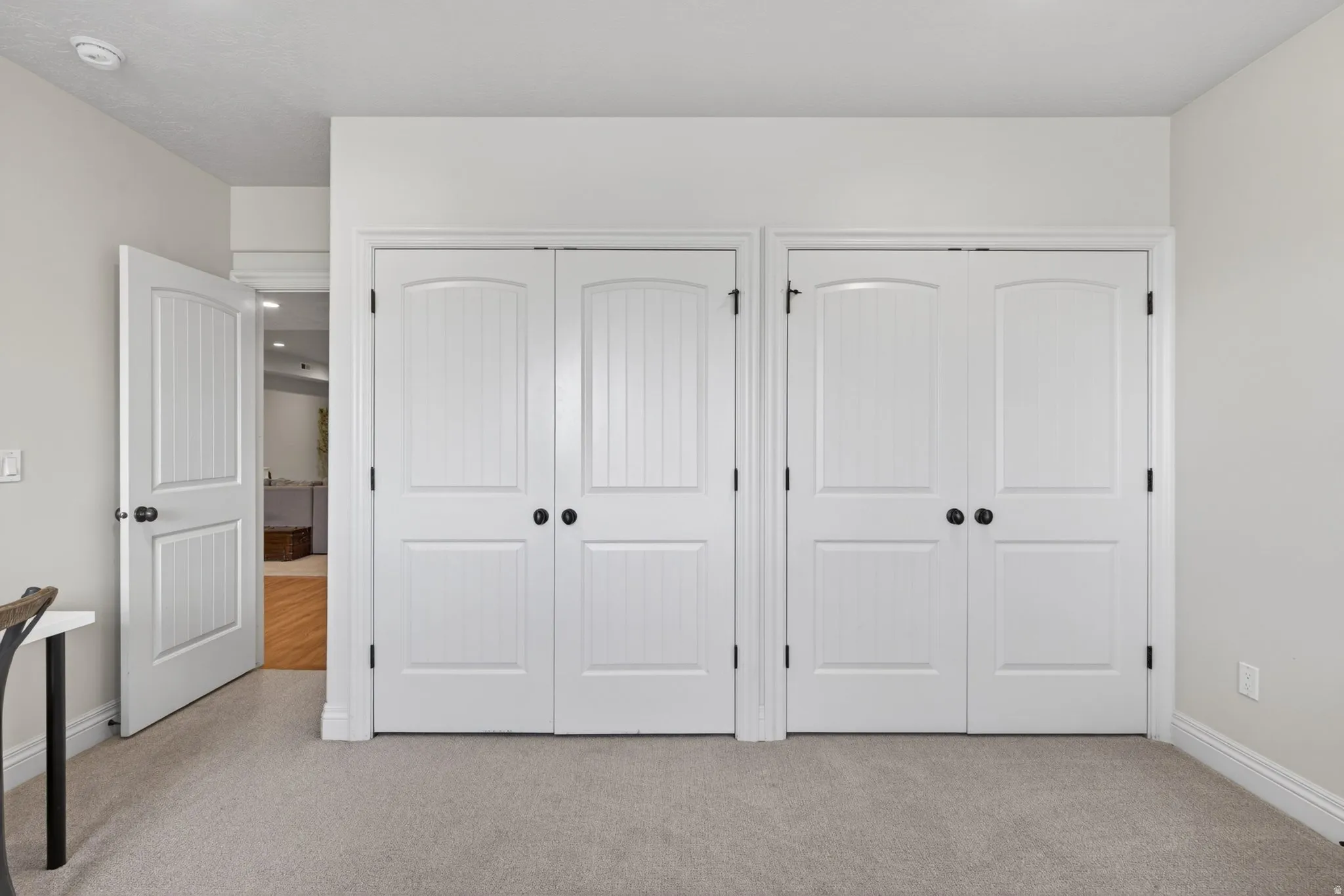 White interior doors with black hardware, arched paneling, and vertical beadboard detailing