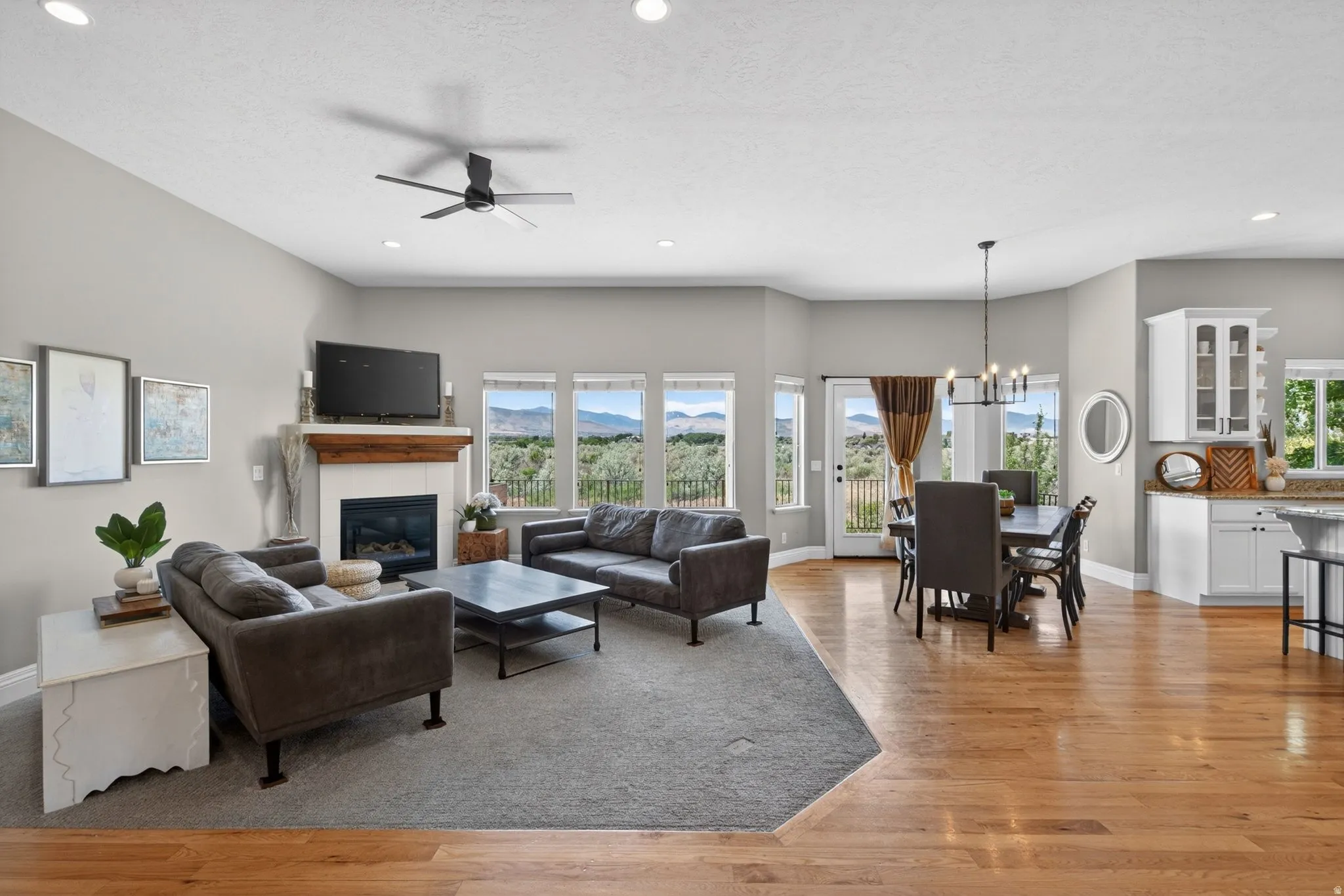 Open-concept living space featuring a fireplace with a wood mantel, a dining area with a chandelier, and a wet bar with white cabinetry and granite countertops