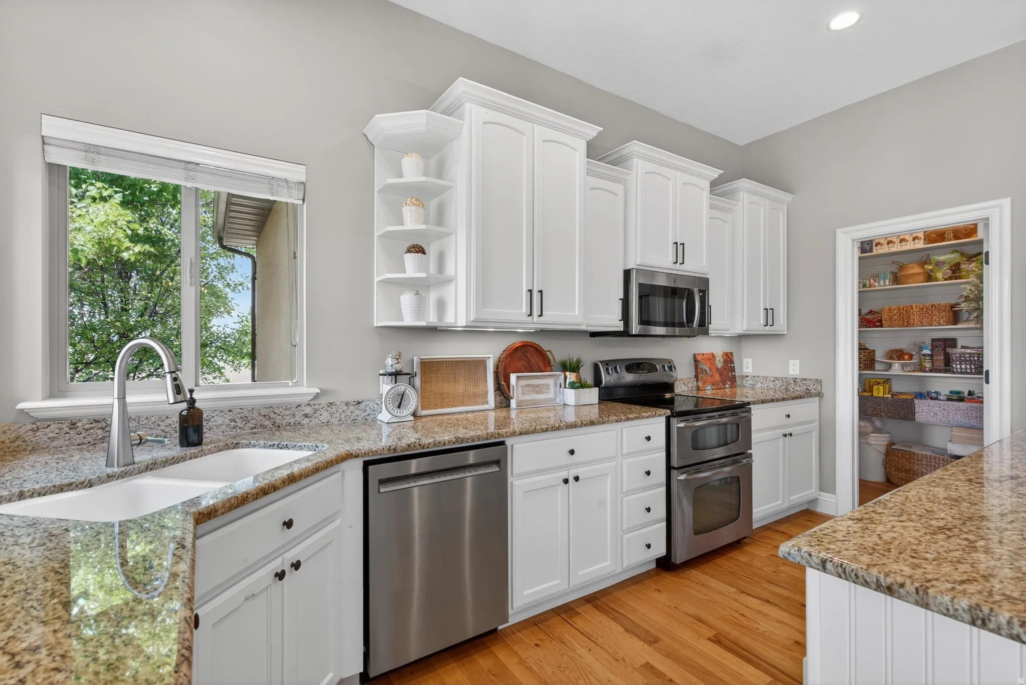 Kitchen featuring white cabinetry, granite countertops, wood-finish flooring, and a walk-in pantry