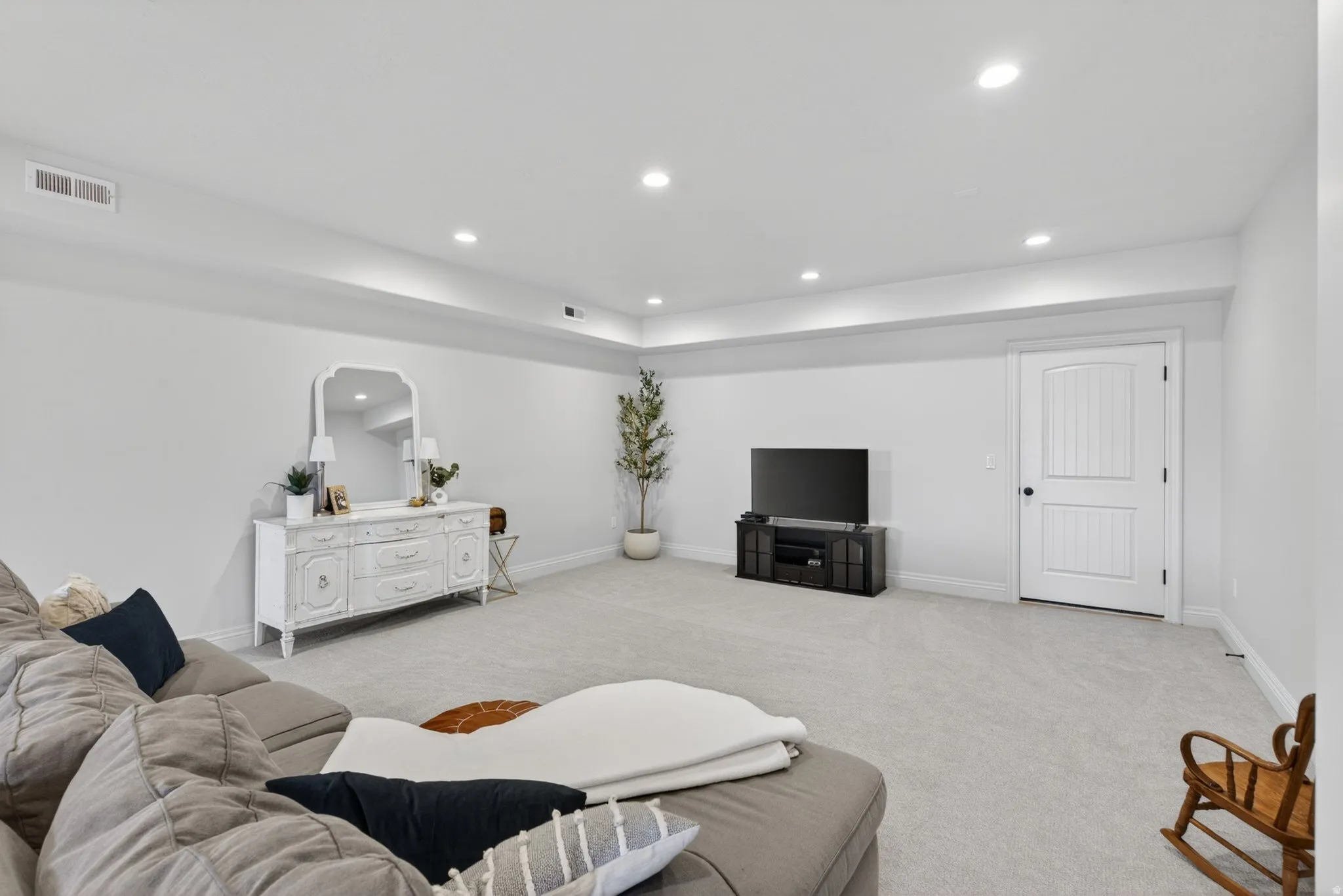 Spacious room featuring light-colored carpeting, white walls, and recessed lighting