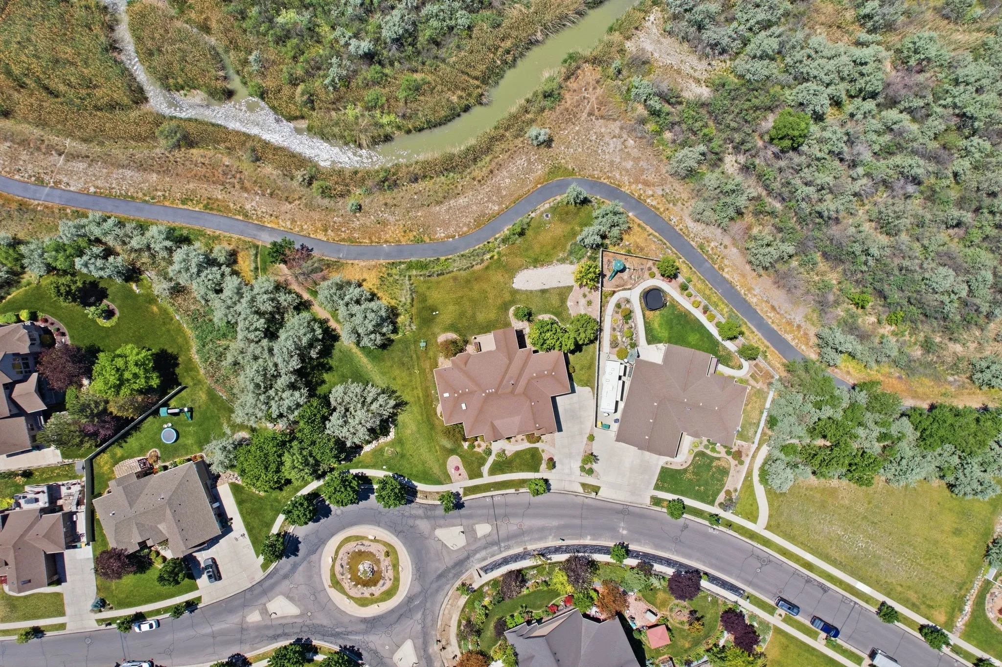 Expansive aerial view showcasing residential properties bordered by a winding paved path and natural landscape