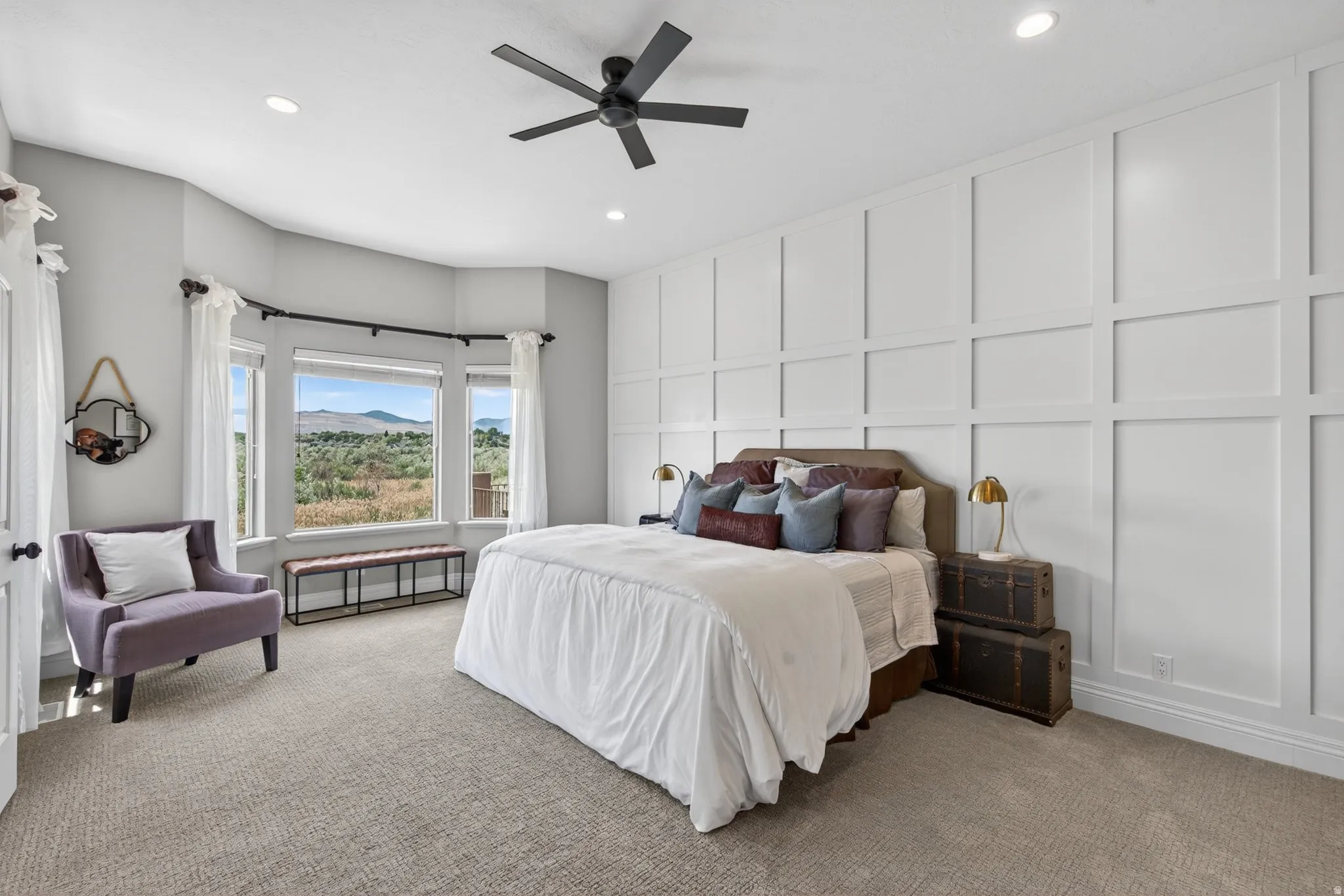 Bedroom featuring a bay window with mountain scenery, board and batten accent wall, recessed lighting, and a ceiling fan