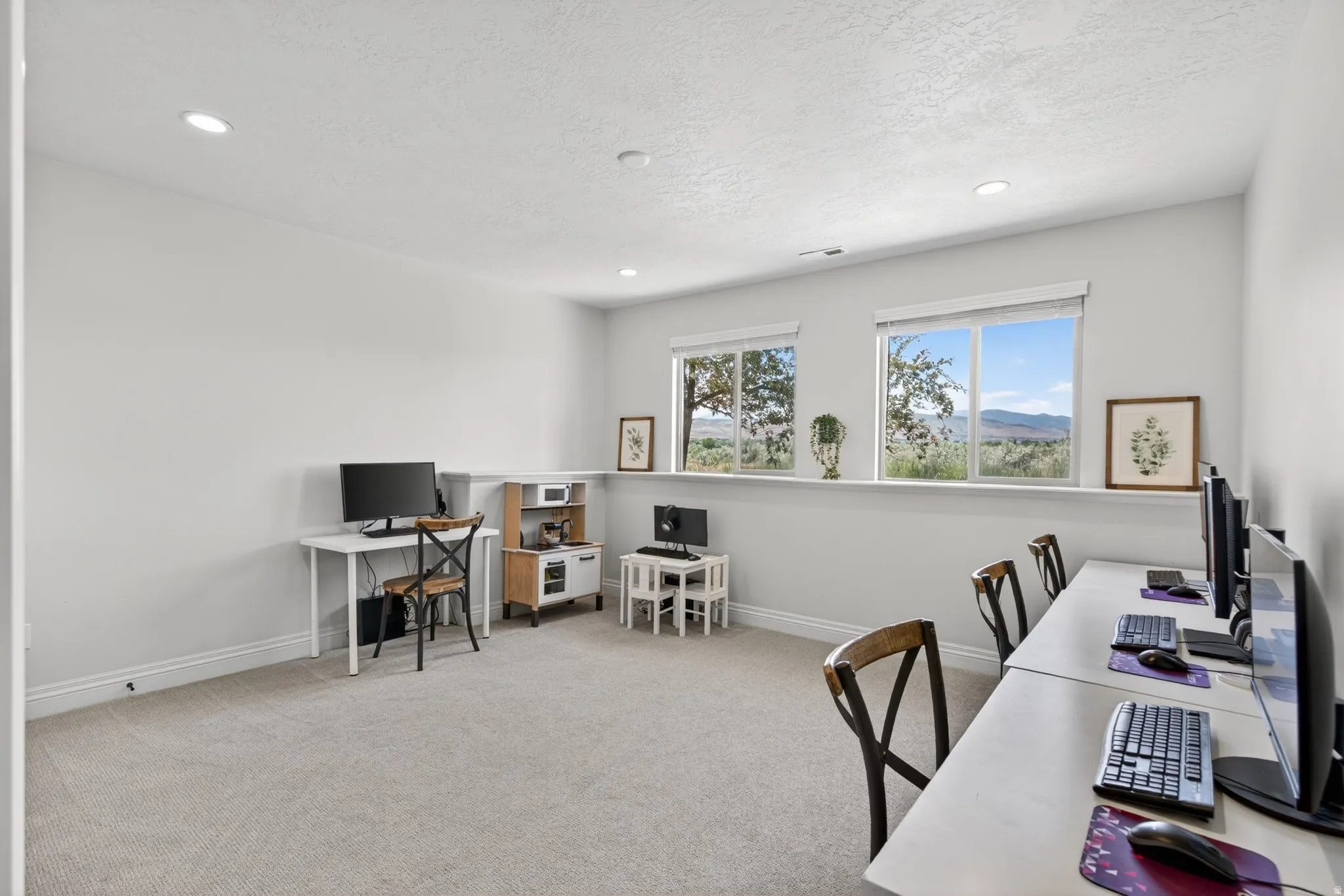 Spacious room featuring light-toned carpet flooring, recessed ceiling lighting, and multiple windows