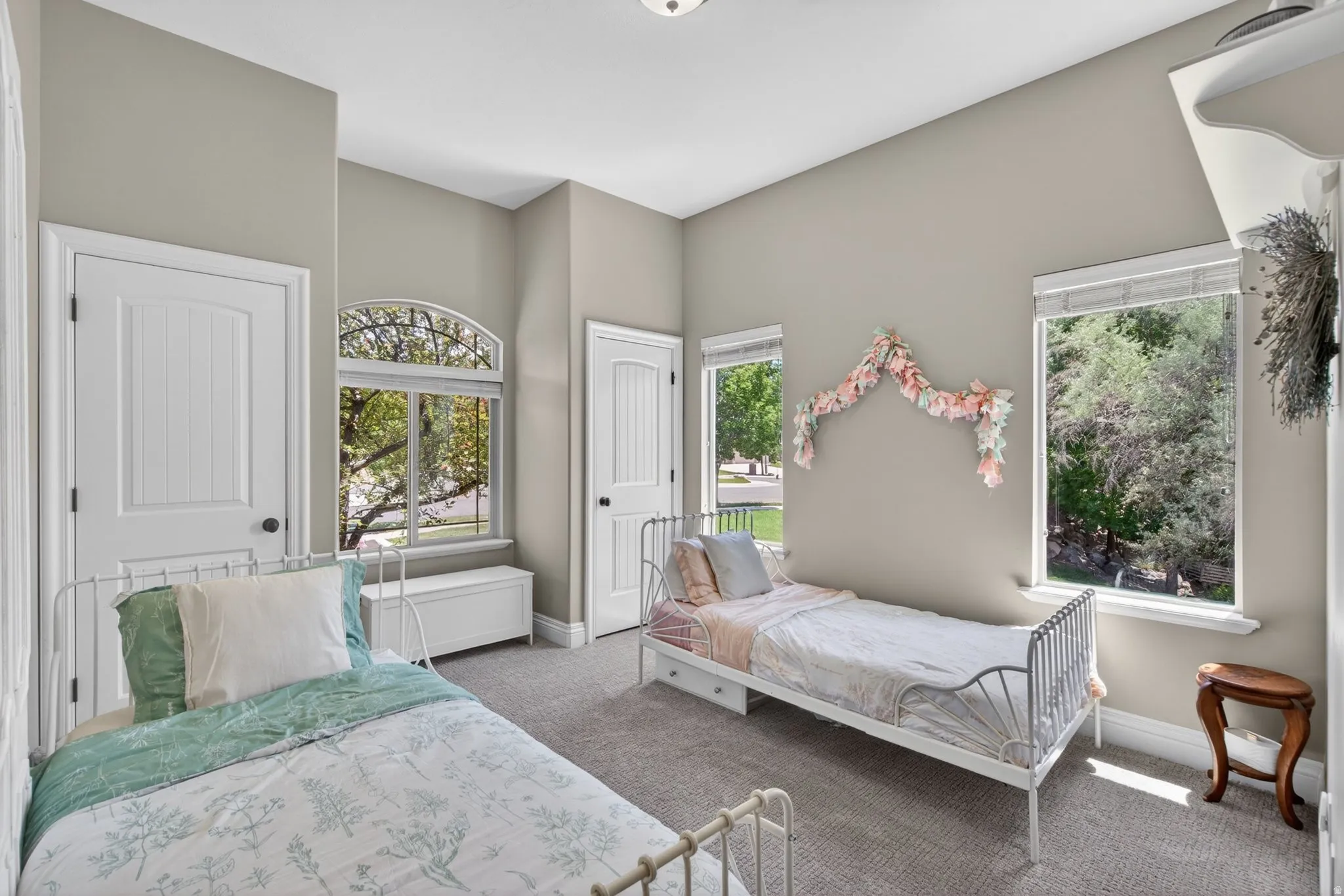 Neutral-toned bedroom featuring plush gray carpeting, white trim, and multiple windows