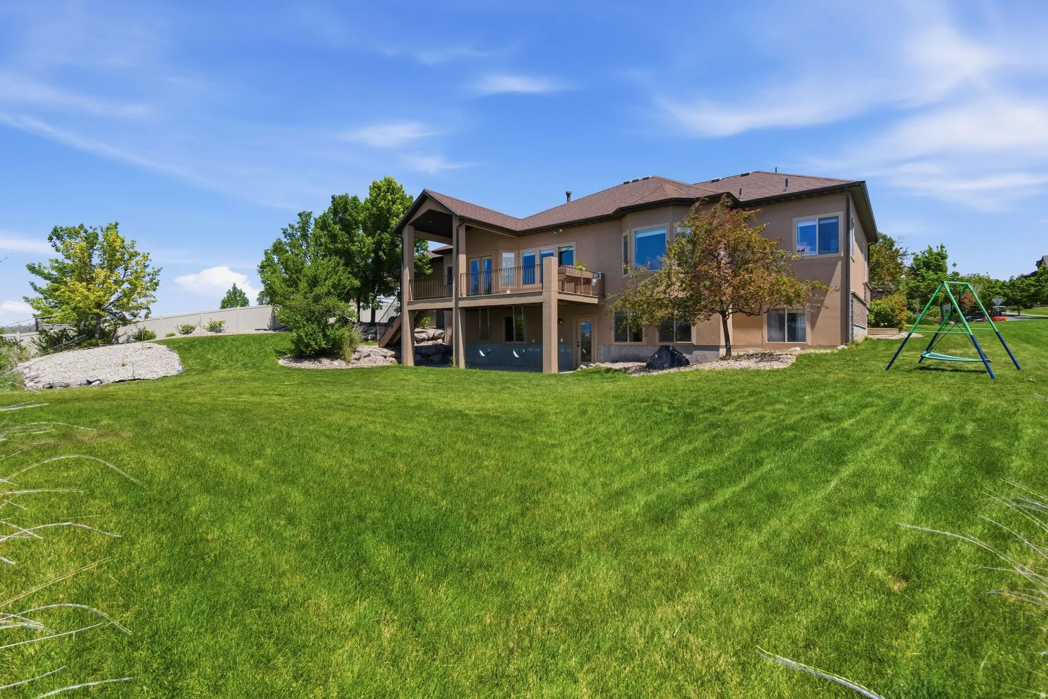 Spacious backyard featuring a manicured lawn, multi-level deck, ground-level patio, and mature landscaping