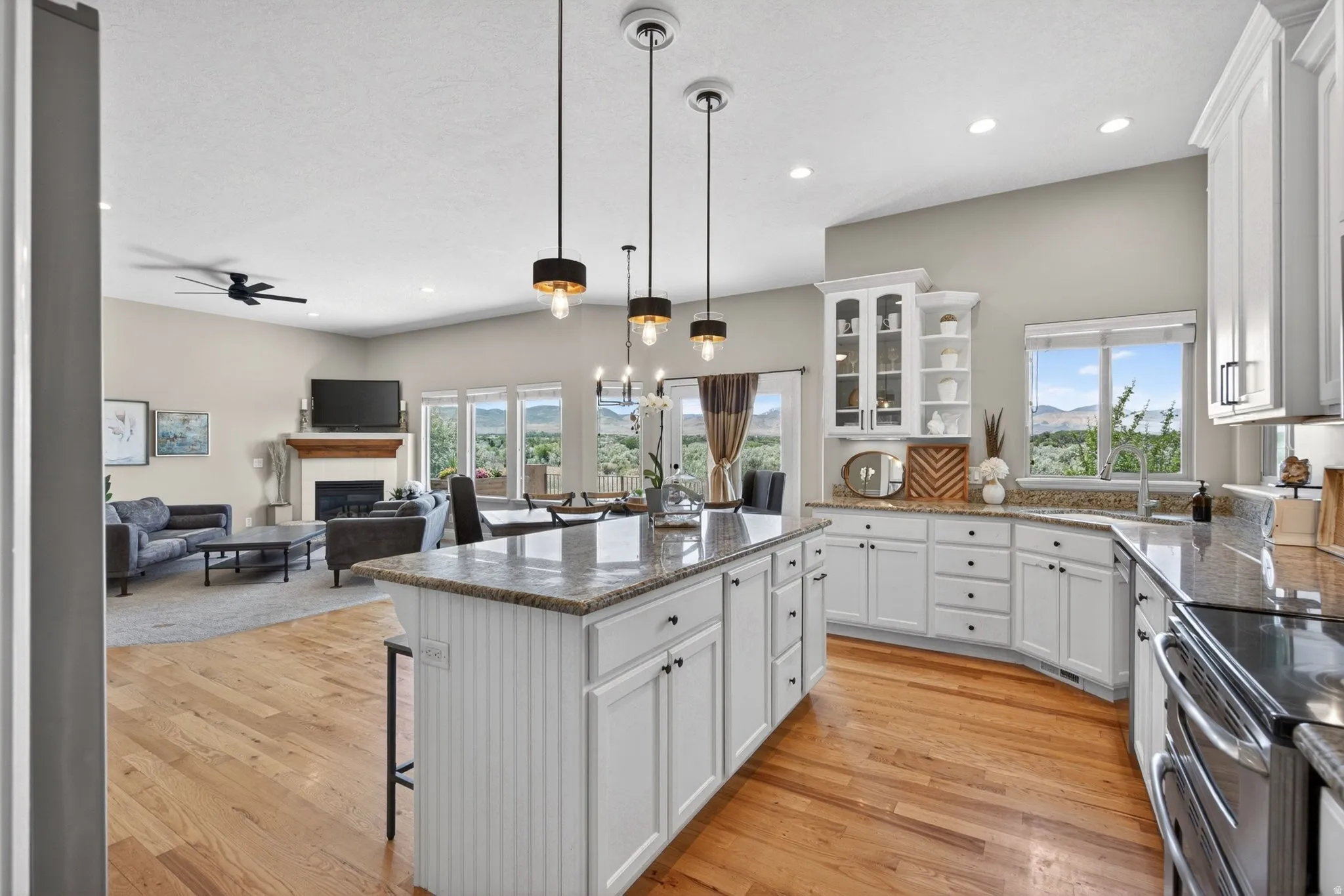 Open-concept living space featuring a central kitchen island with beadboard paneling, white cabinetry, and granite countertops
