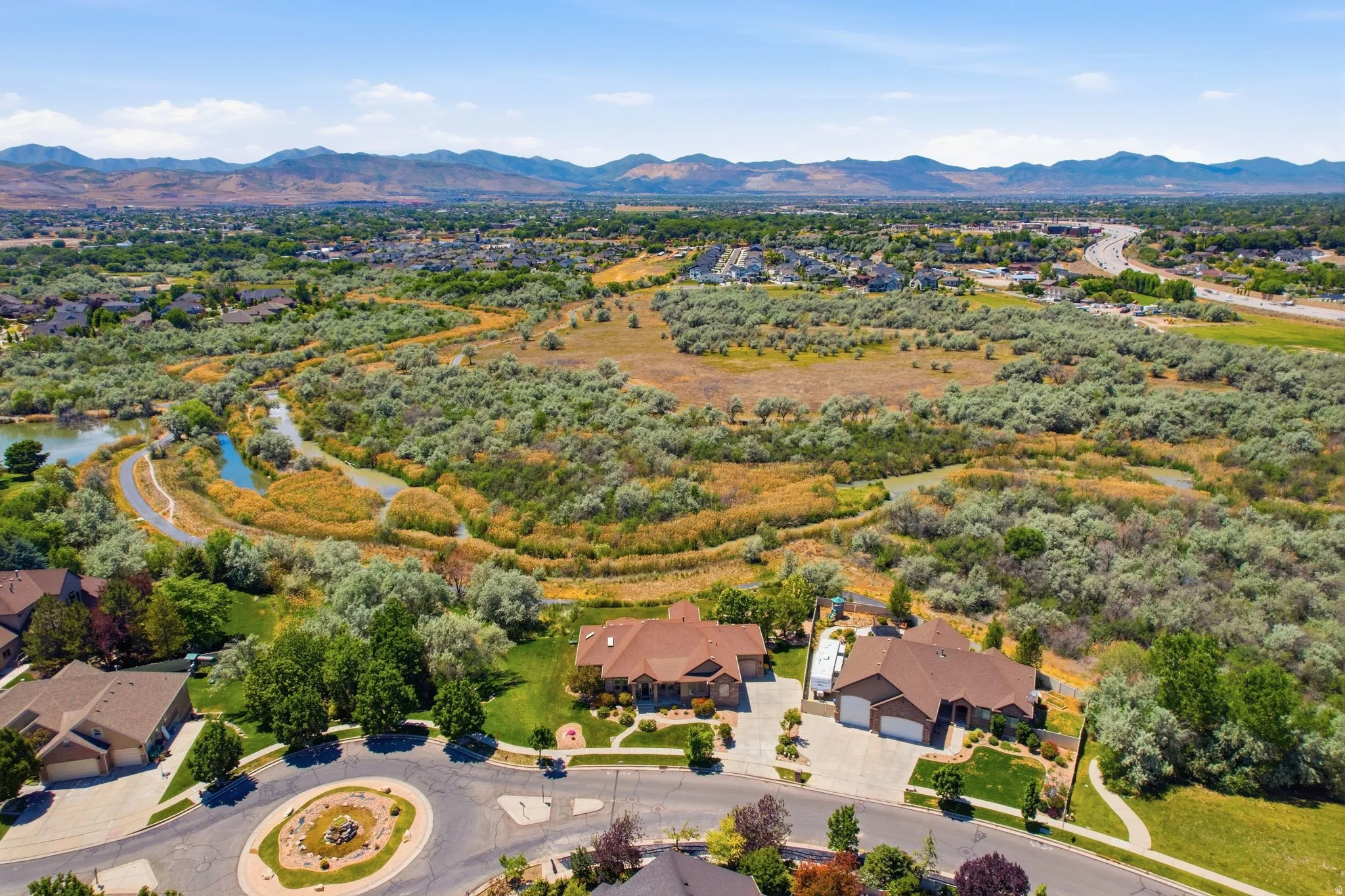 Expansive natural landscape featuring a winding river, dense foliage, and distant mountains