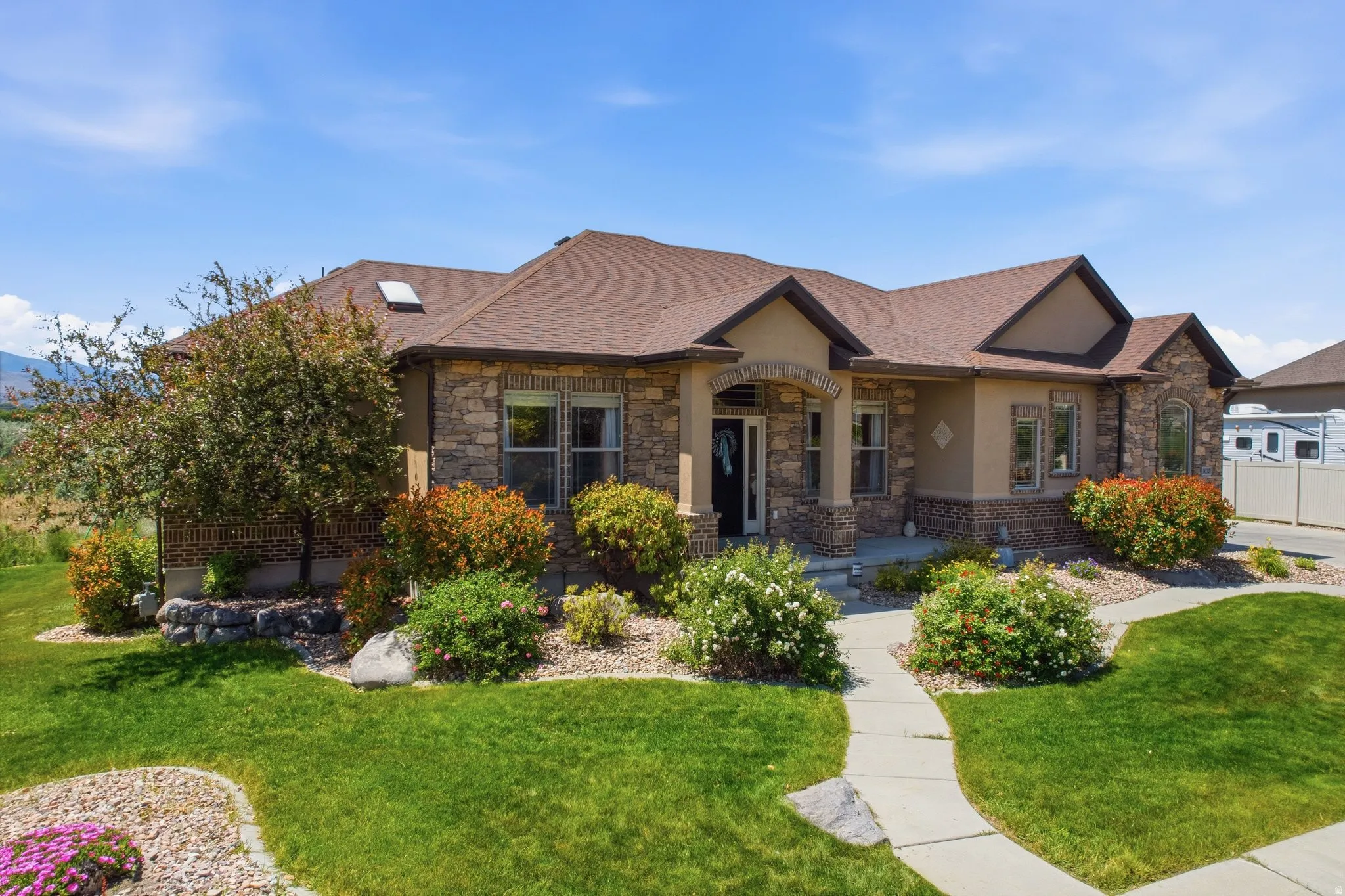 Ranch-style residence featuring a stone and stucco exterior, a brown shingle roof, and a skylight