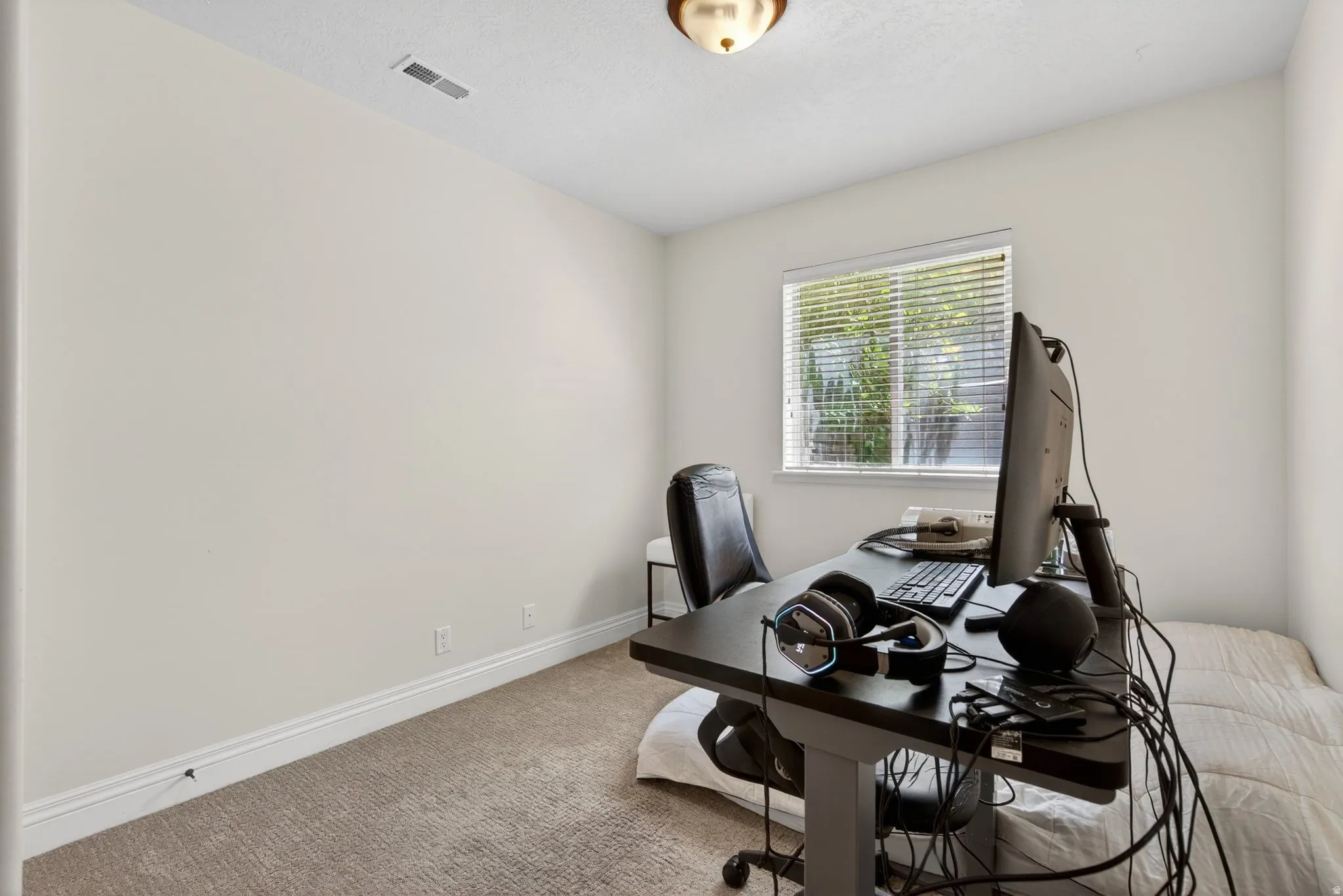 Light-filled room featuring neutral-toned walls, a single window with blinds, and recessed lighting