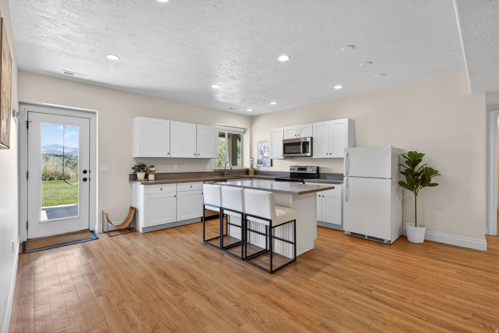 Bright kitchen featuring white cabinetry, a center island with seating and wood-finish flooring