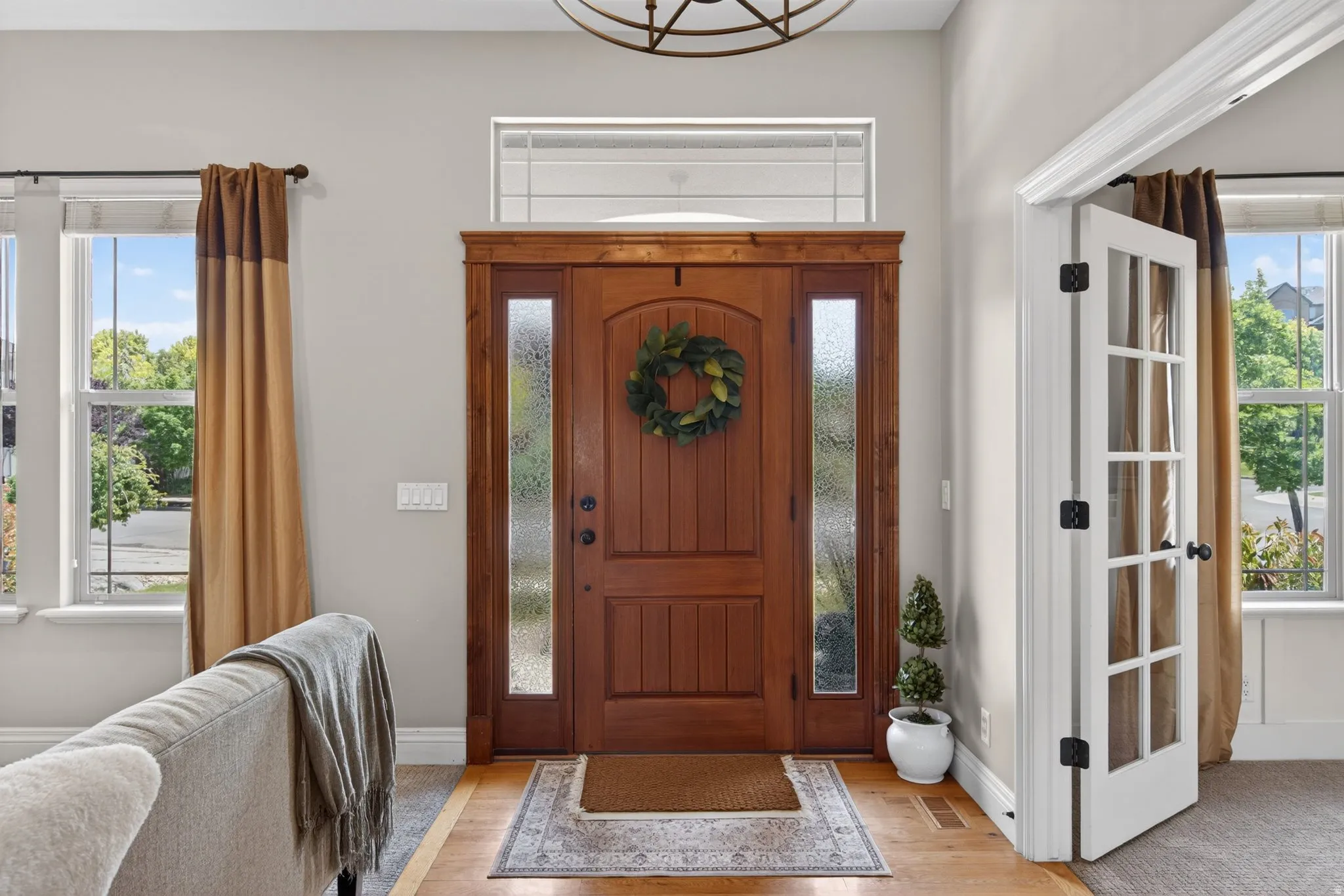 Arched wood-panel front door with textured glass side panels and transom window