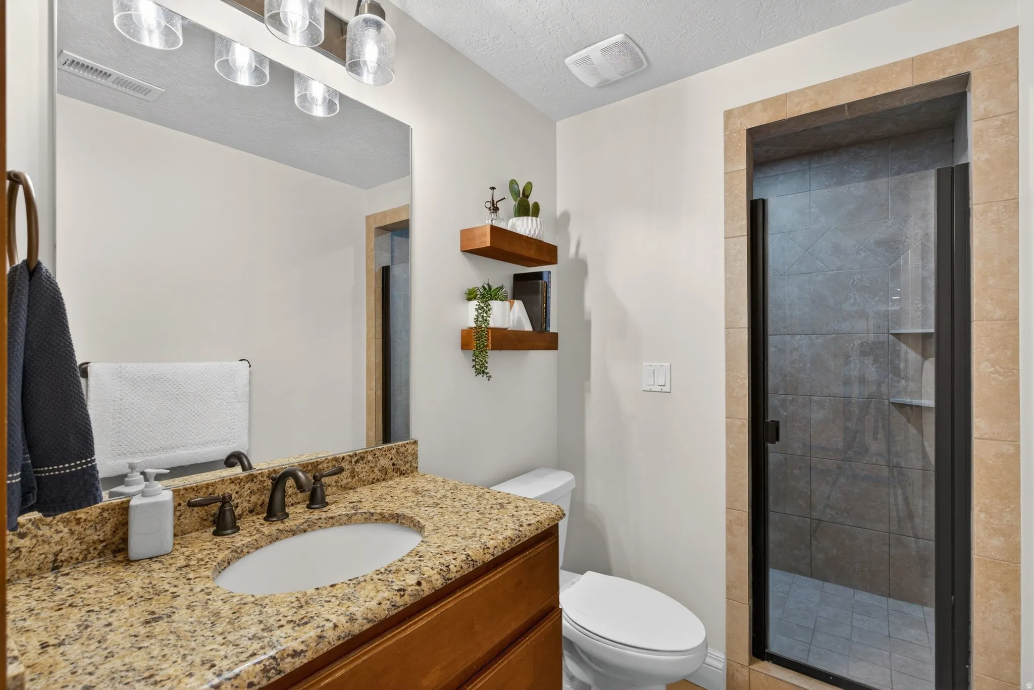 Bathroom featuring a granite-finish vanity with an undermount sink, oil-rubbed bronze faucet, and a frameless mirror