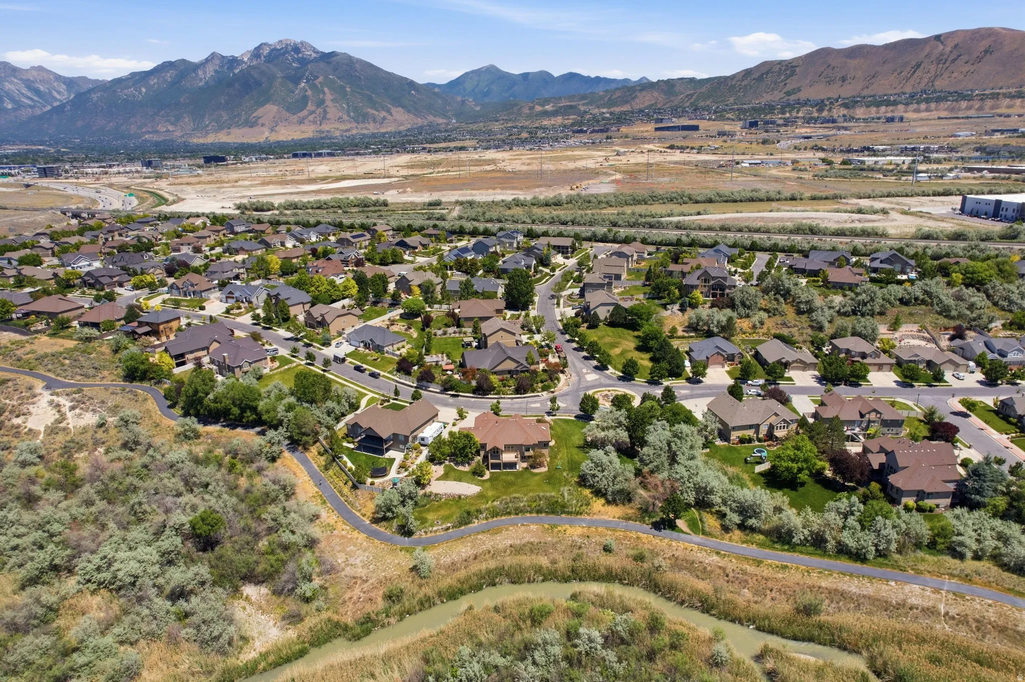 Residential neighborhood featuring varied home styles, tree-lined streets, and a paved walking path