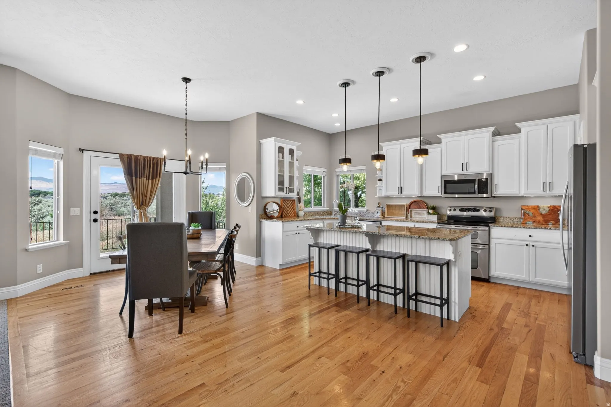 Open-concept kitchen and dining area featuring light wood-finish flooring, white cabinetry, and recessed lighting