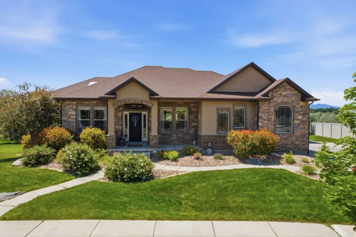 Stone and stucco exterior residence featuring a covered entry, arched stone accents, and a brown shingle roof
