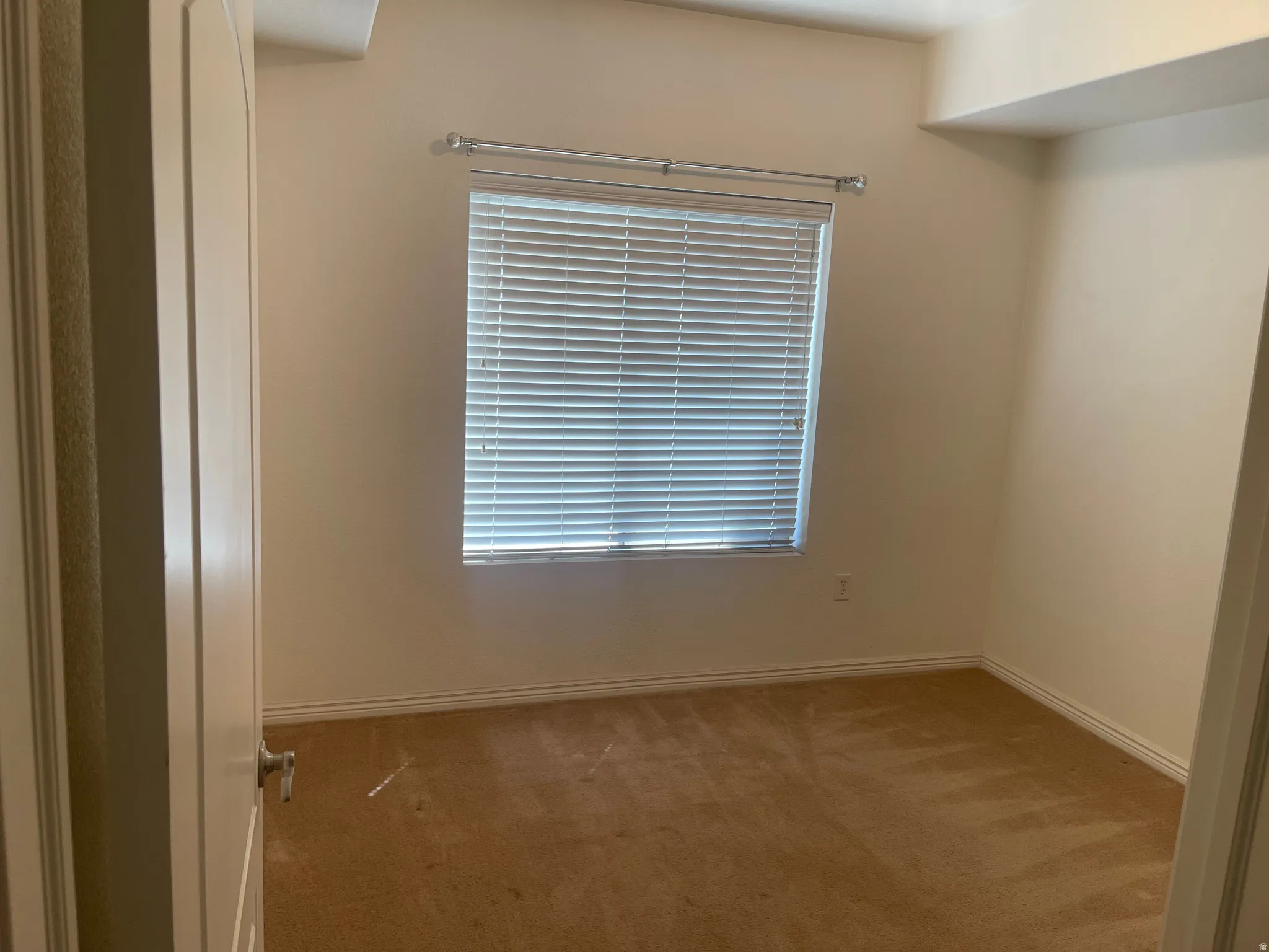 Room featuring a single window with horizontal blinds, carpet flooring, and neutral-toned walls
