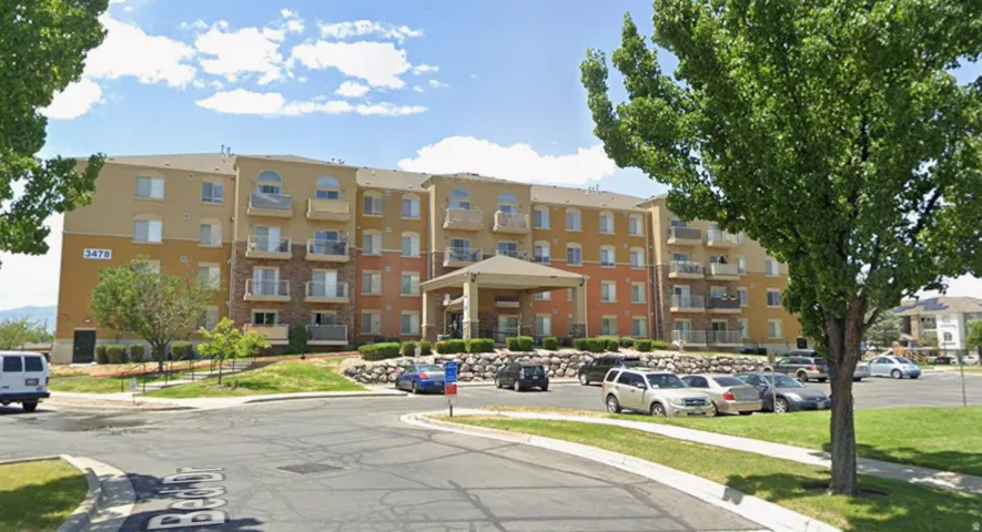 Multi-story building featuring a stucco and stone veneer exterior, multiple balconies with metal railings, arched windows, and a covered entry
