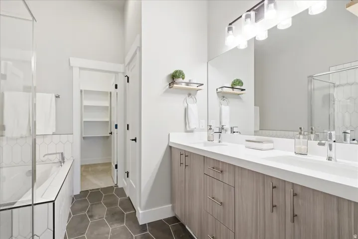 Bathroom featuring a dual vanity with light wood-finish cabinetry, white countertop, and integrated sinks