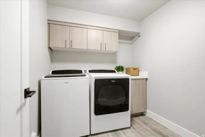 Dedicated laundry area featuring wood-finish flooring, light wood-grain cabinetry, and a countertop space