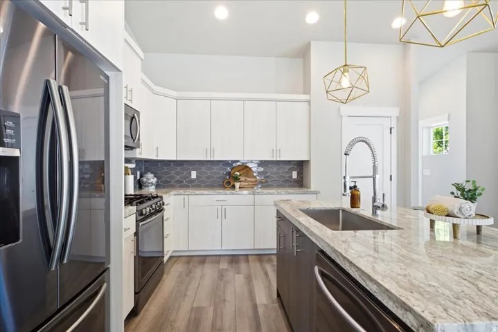 Contemporary kitchen featuring a large island with an undermount sink, light-colored countertops, and a gray backsplash