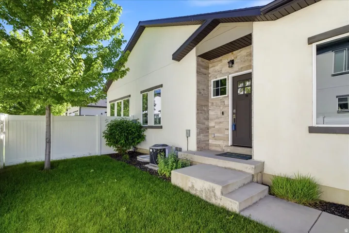 Stucco exterior featuring a stone accent entry, dark brown entry door with window panes, dark trim, and multiple windows