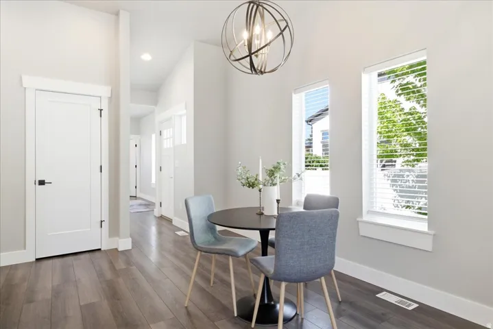 Open-concept dining area featuring vaulted ceilings, wood-finish flooring, and multiple windows with white blinds