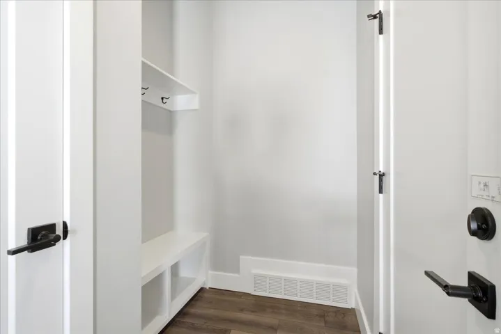 Mudroom featuring built-in bench storage, wall-mounted coat hooks, and durable wood-finish flooring