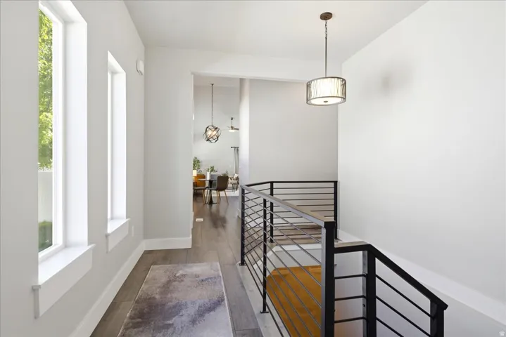 Modern interior hallway with wood-finish flooring, white walls, and multiple vertical windows