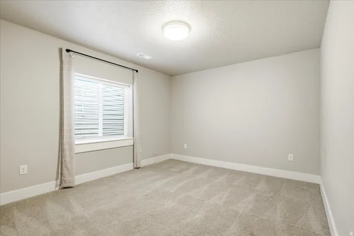 Bright room featuring neutral-toned walls, carpet flooring, a window with horizontal blinds, and a flush mount ceiling light fixture