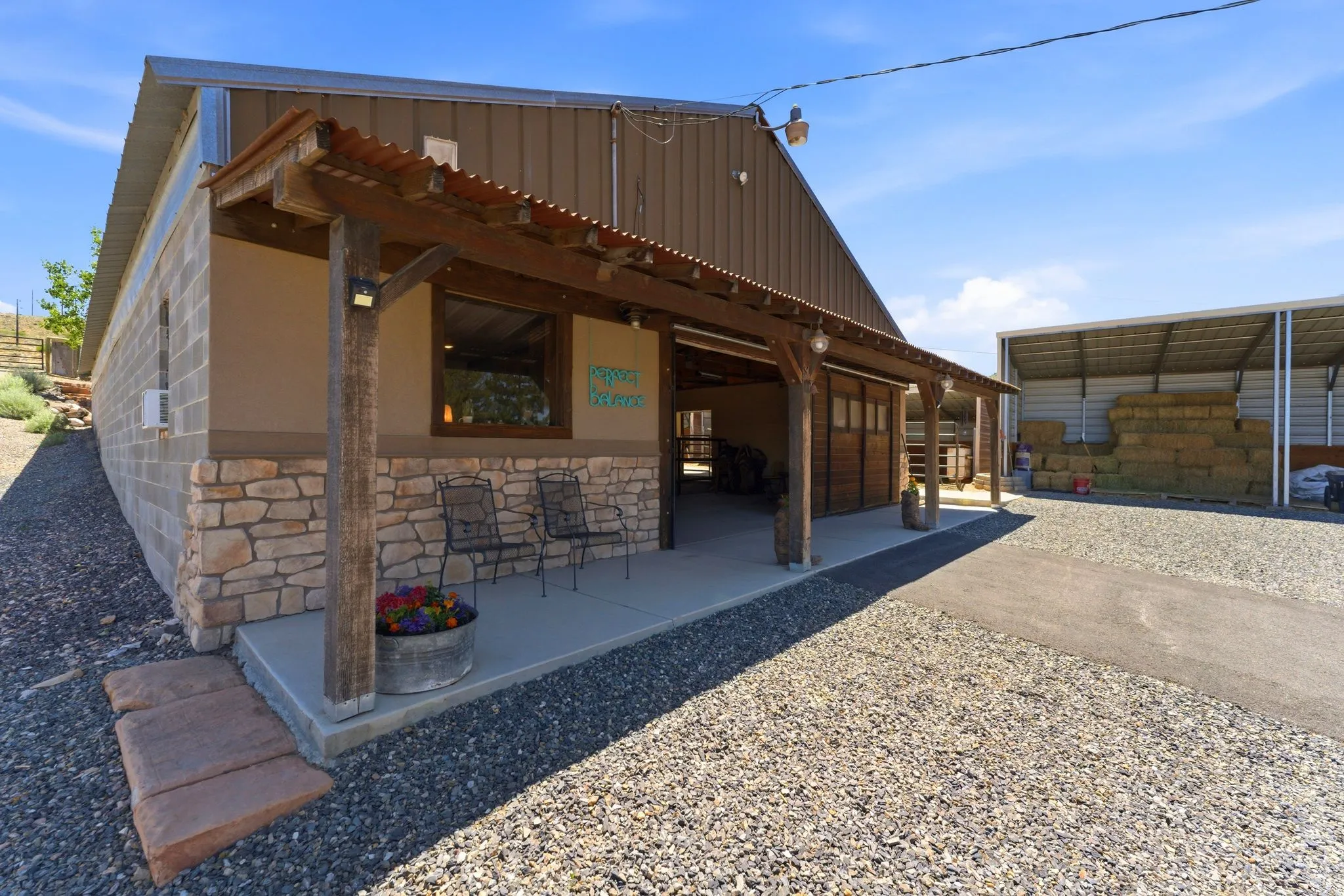 Barn-style structure featuring a corrugated metal roof over a covered concrete patio