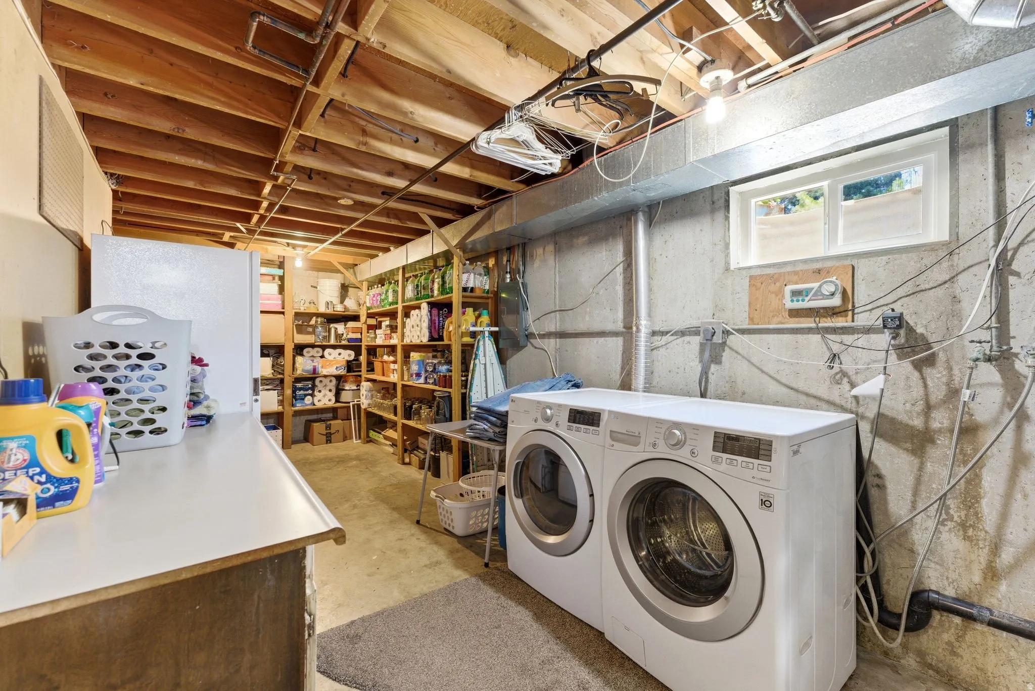 Basement utility area featuring exposed wood joists and concrete walls