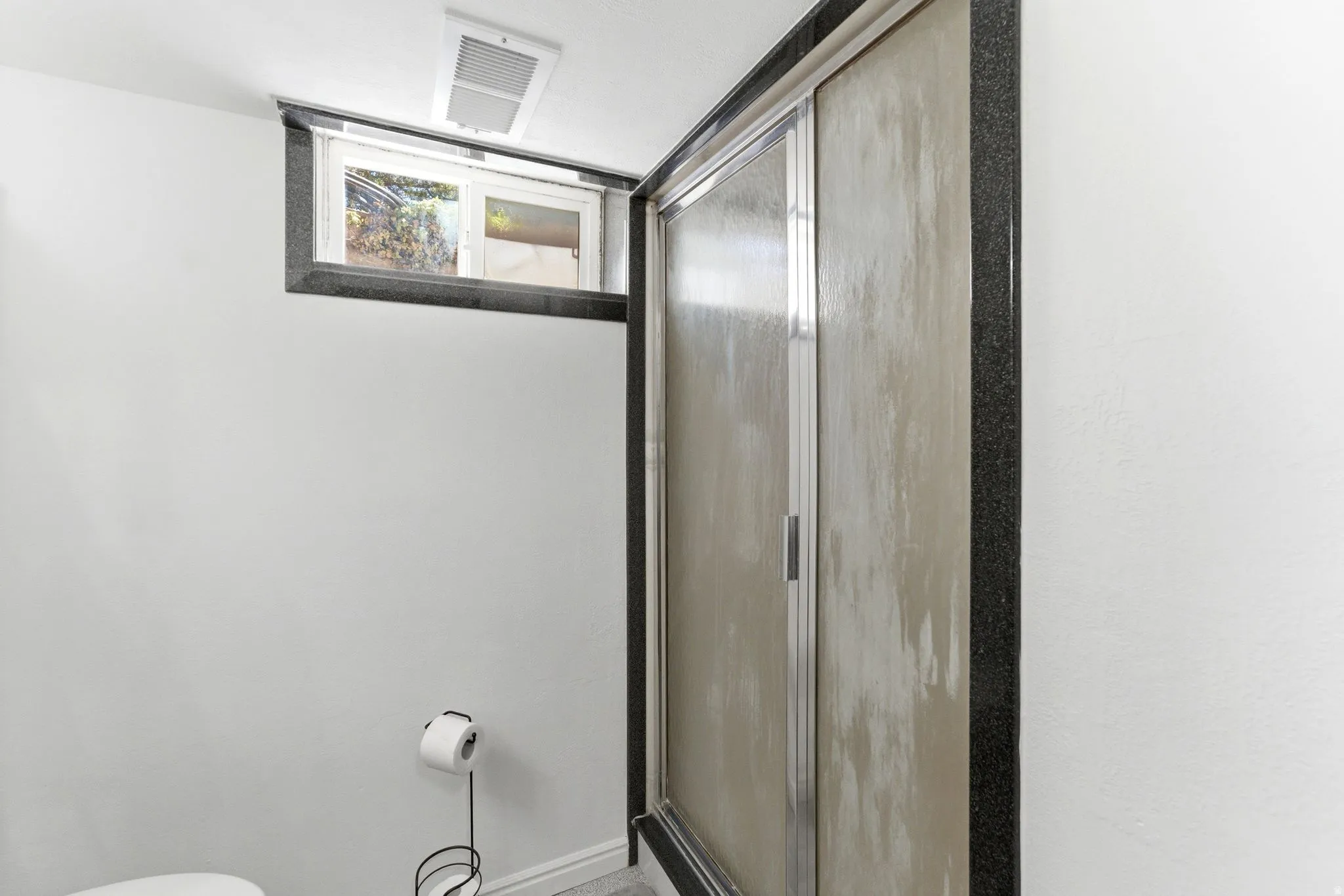 Shower enclosure with frosted glass panels, aluminum frame, and black speckled trim
