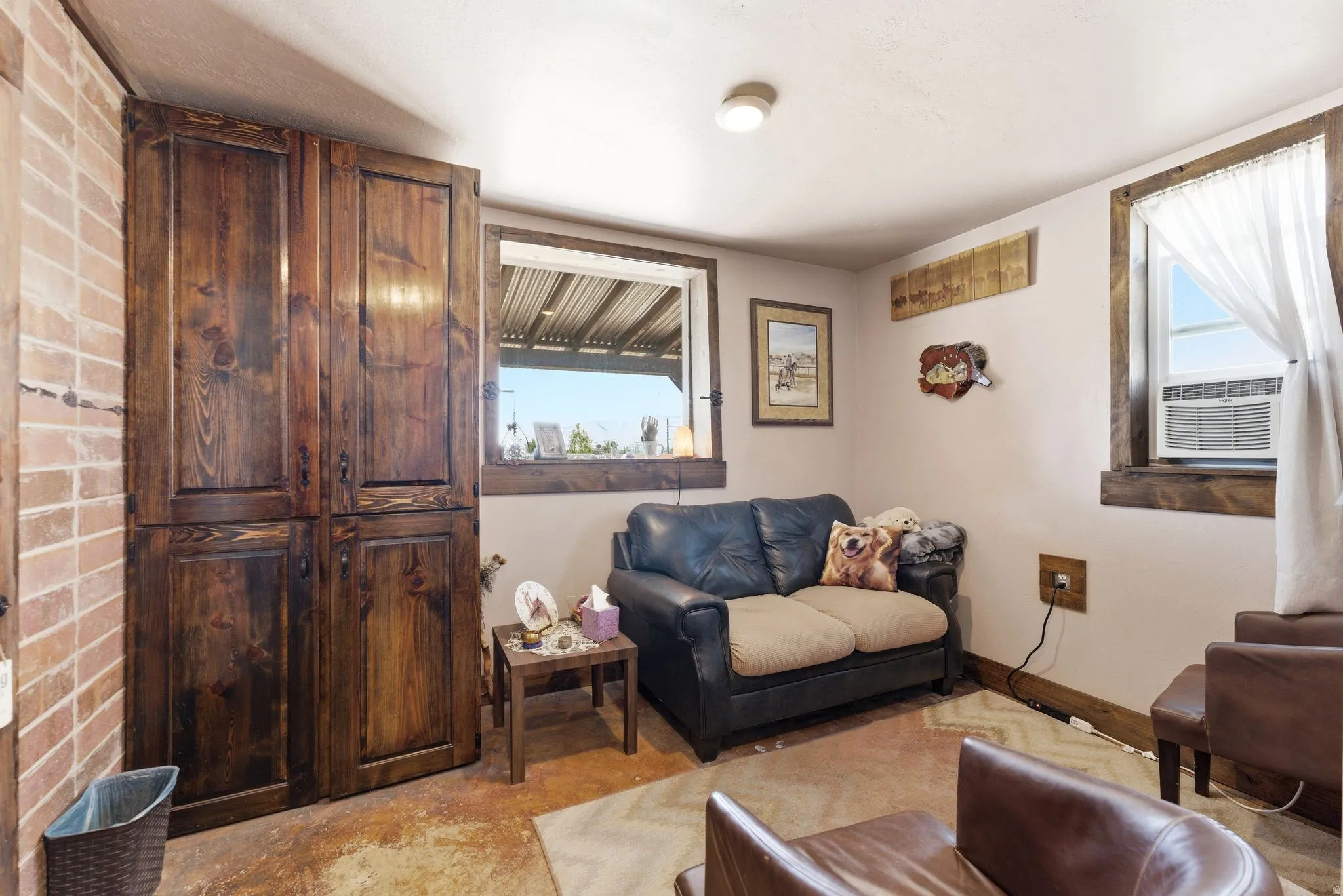 Built-in wood cabinetry with dark finish, exposed brick wall accent, wood window trim, and a window air conditioning unit