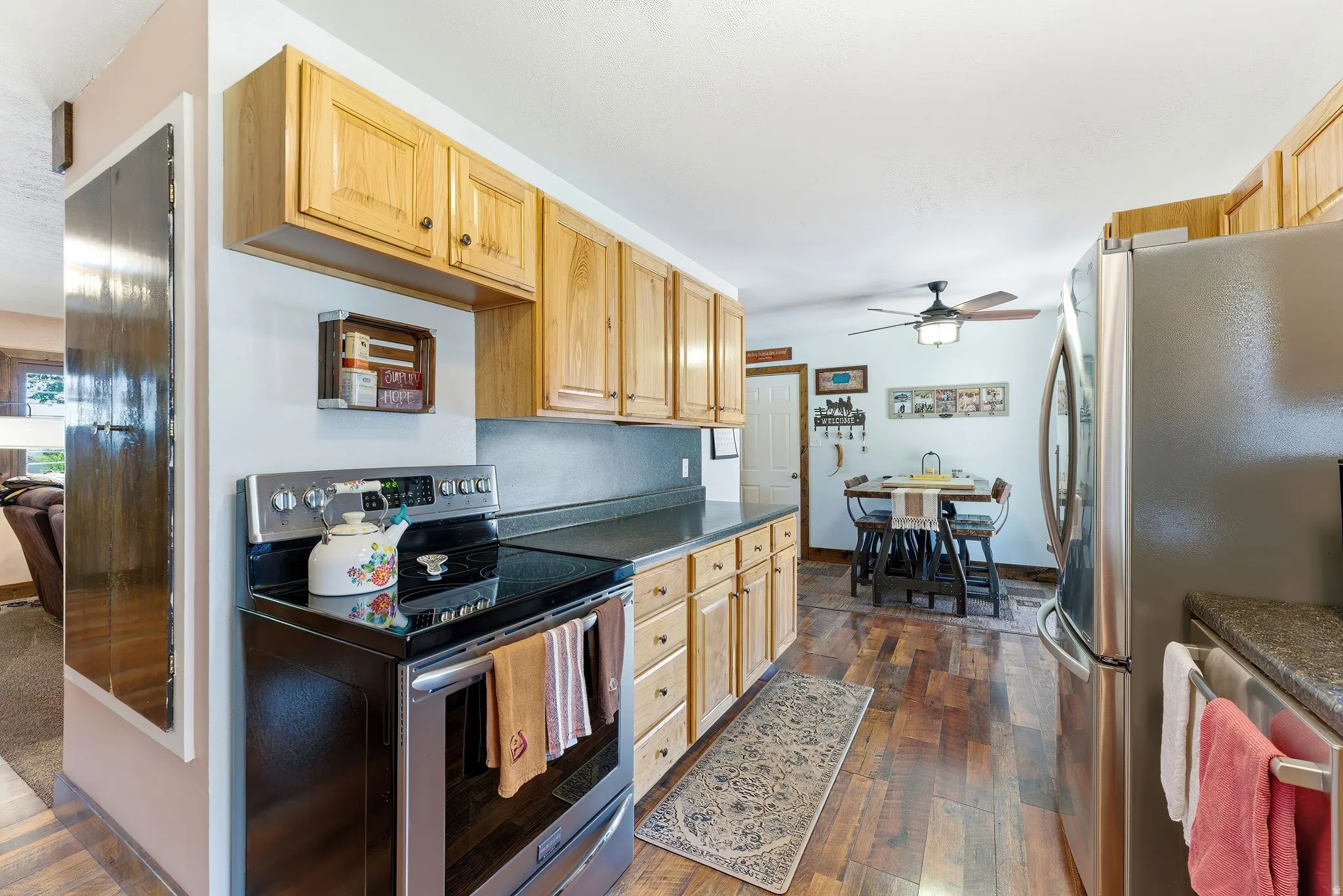 Kitchen featuring natural wood cabinetry, black countertops, and wood-finish flooring