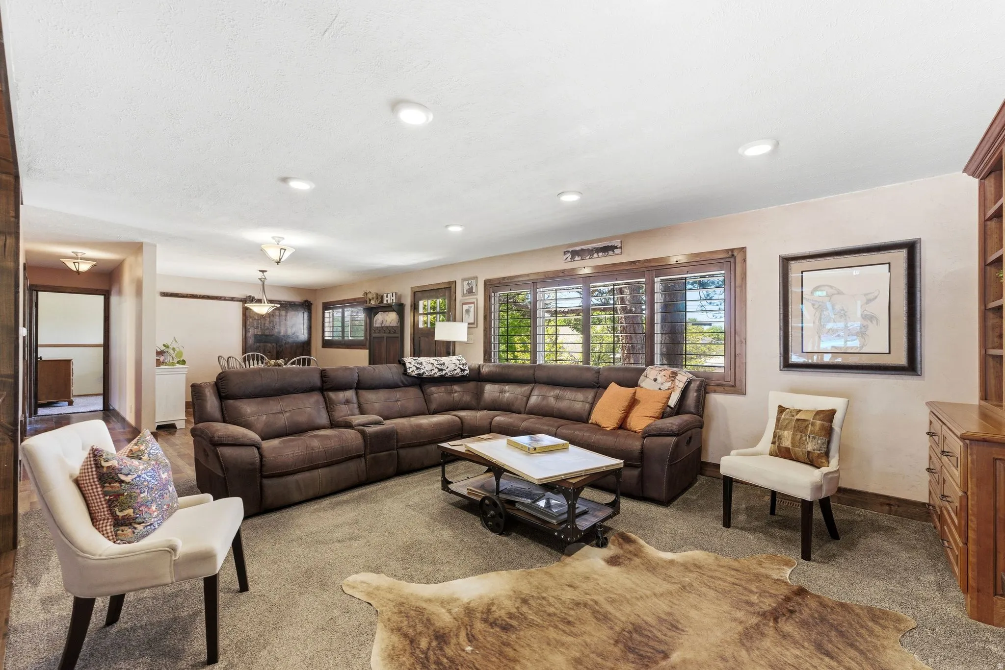 Living area featuring neutral-toned carpeting, wood-finish flooring, recessed lighting, and a built-in wood-finish shelving unit with drawers