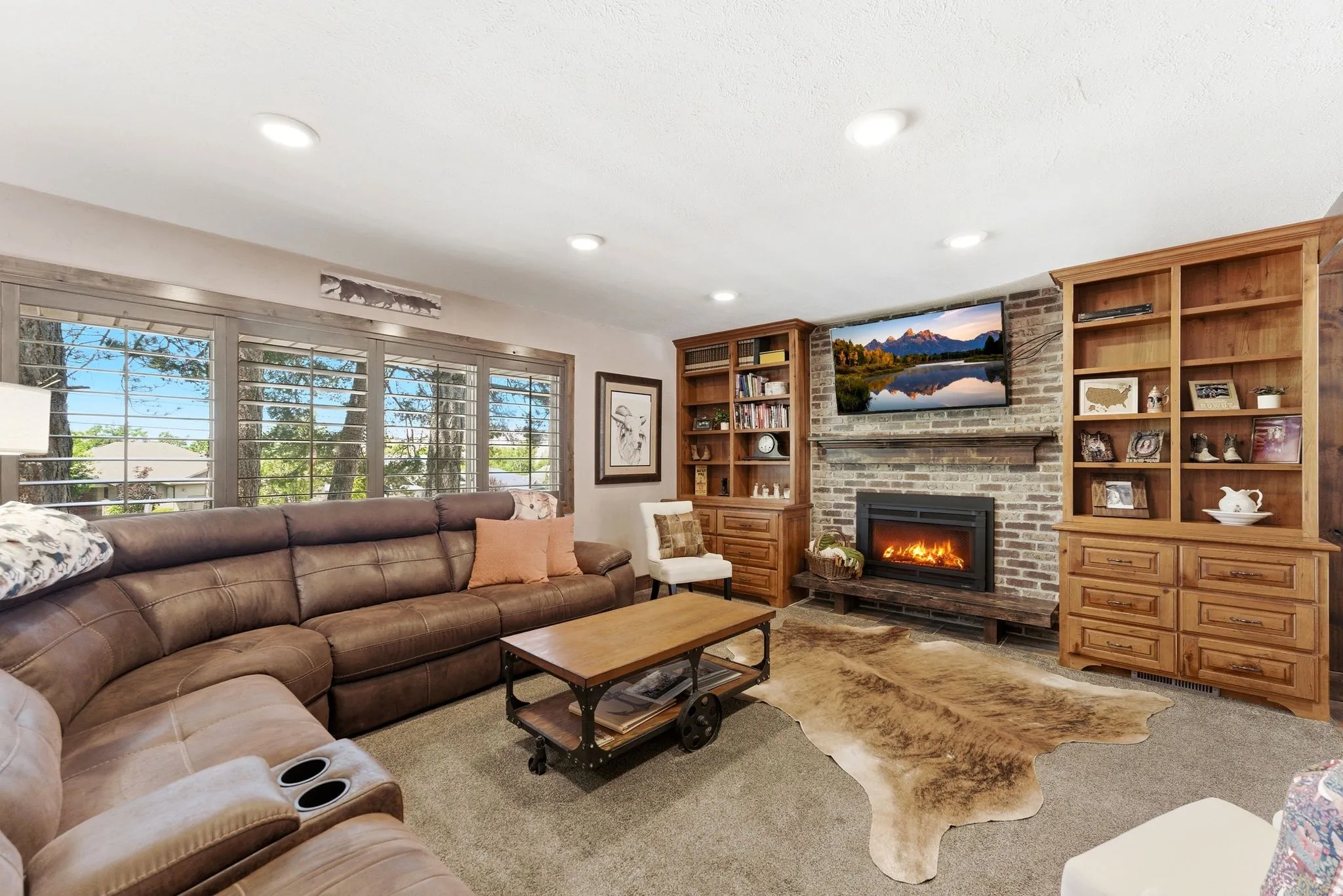 Living area featuring a brick-surround fireplace with a wood mantel, flanked by built-in wood cabinetry