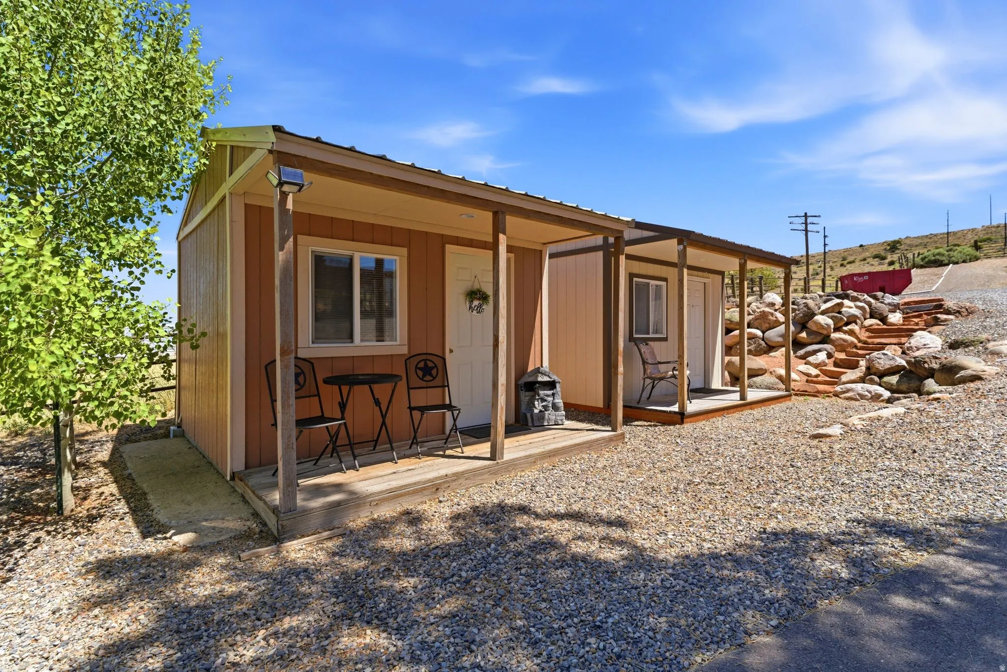 Exterior structure featuring a covered porch, gravel landscaping, and a wooden staircase