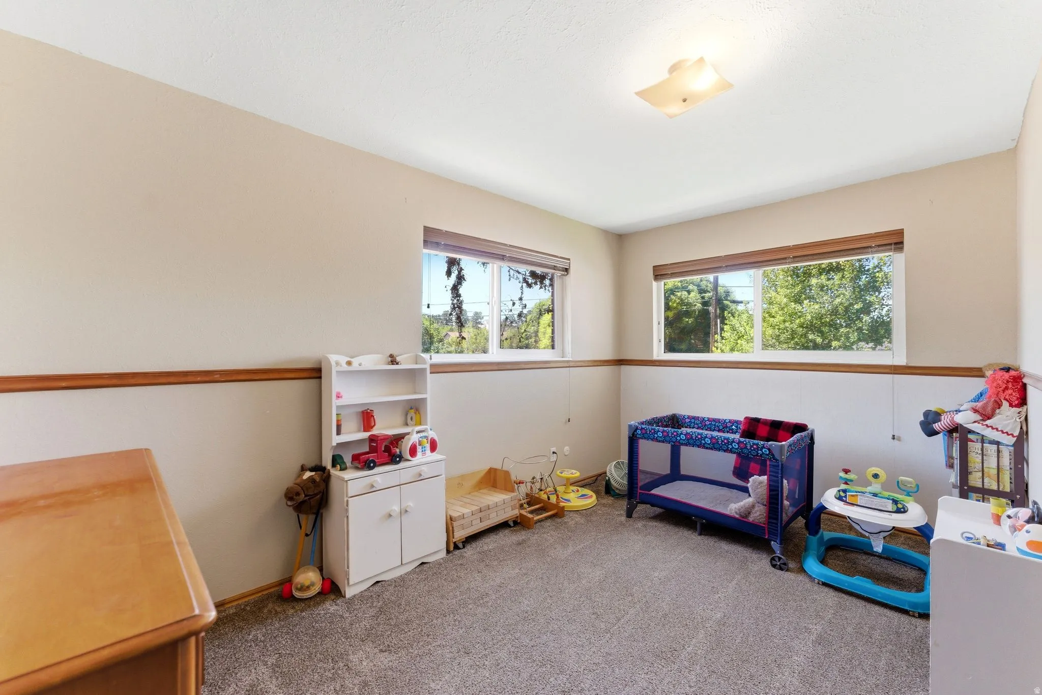 Spacious room featuring neutral walls, wood-finish chair rail molding, and large windows with natural light