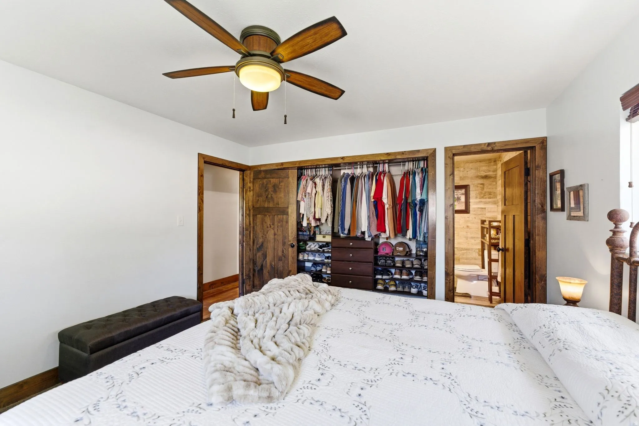 Room featuring a wood-finish ceiling fan with integrated lighting, a built-in closet with sliding wood-finish doors and interior shelving, and wood-finish door frames