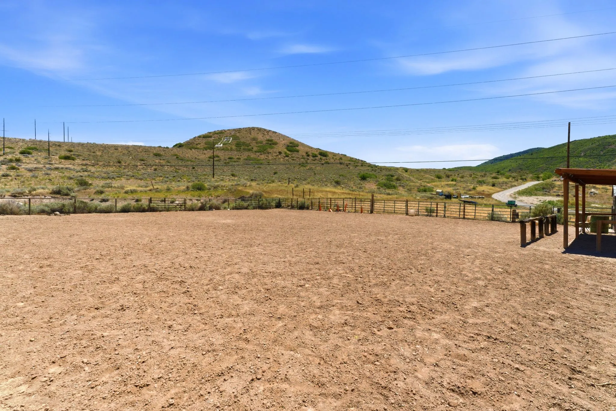 Expansive unpaved lot with wood fencing and a covered outdoor structure