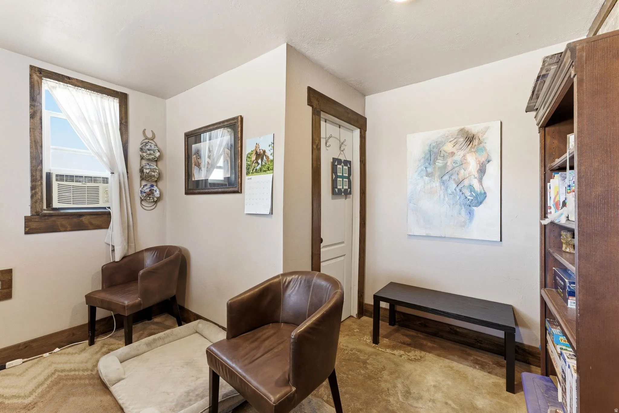 Room featuring a window with wood-finish trim, a paneled door with wood-finish trim, and a built-in bookshelf