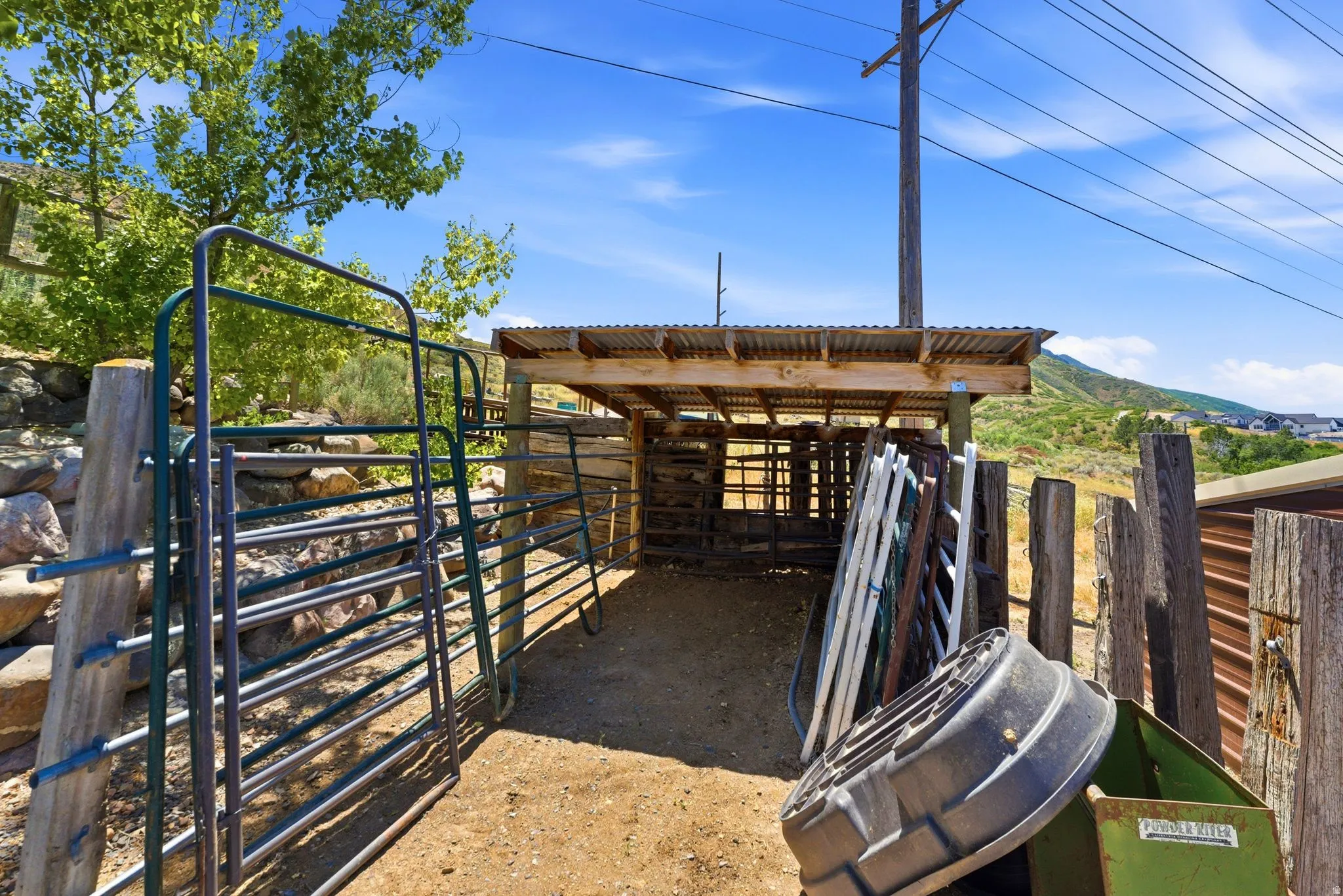 Open-air animal enclosure featuring a corrugated metal roof and wood post construction