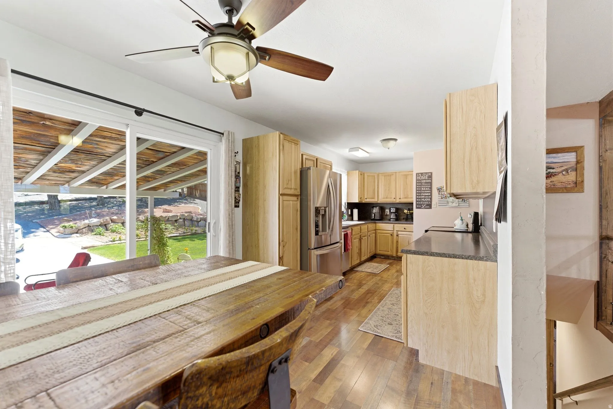 Open-concept kitchen and dining area featuring wood-finish flooring, light wood cabinetry, and stainless steel appliances