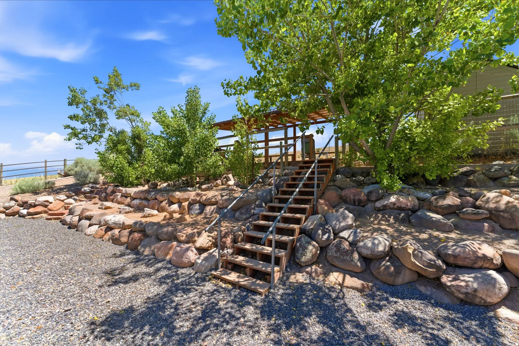 Terraced landscaping featuring natural stone retaining walls, gravel ground cover, and mature trees
