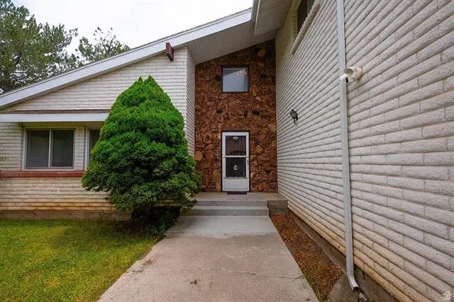 Entryway featuring a concrete walkway, stone facade accents, and light-colored brick siding